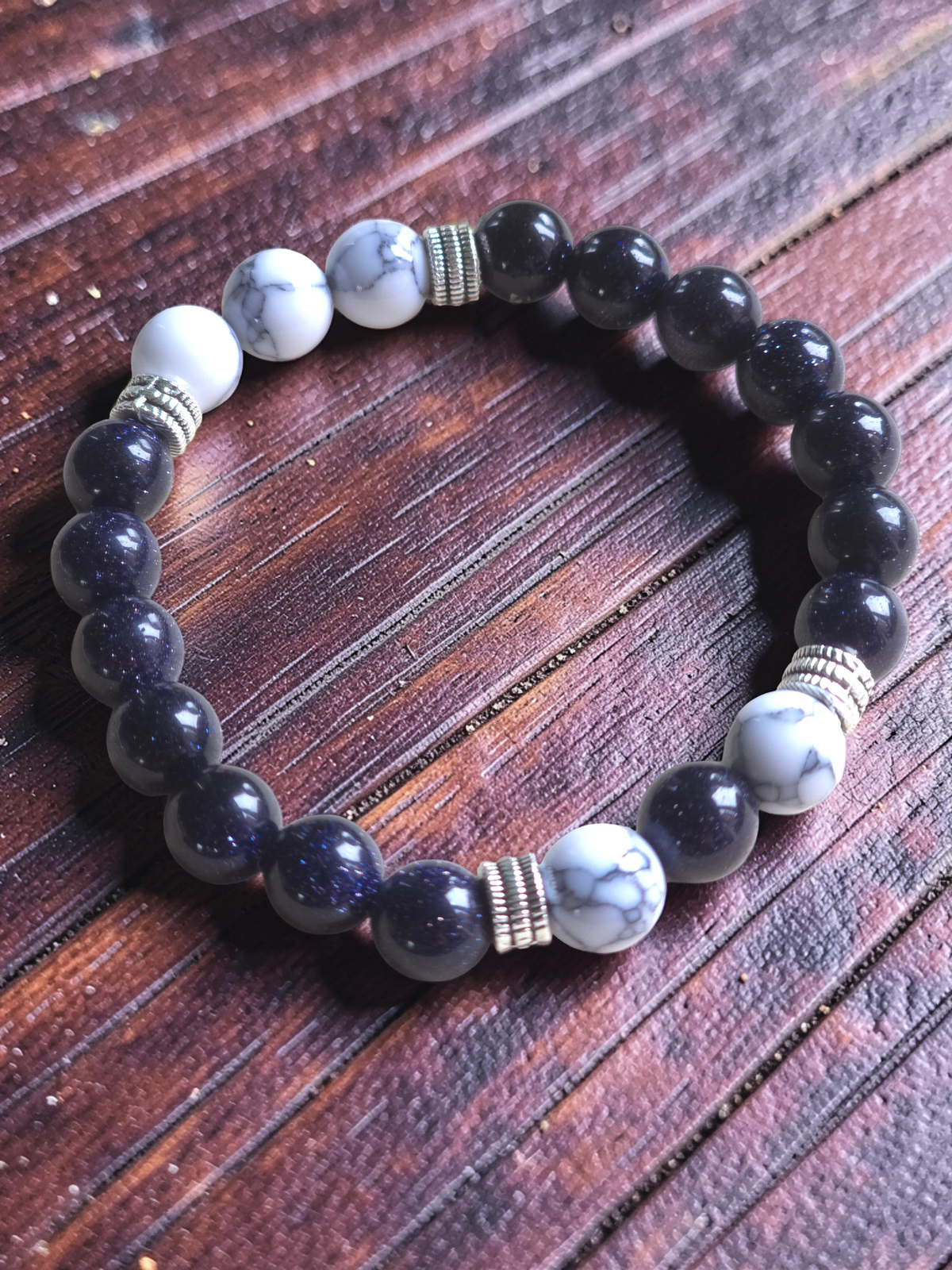 Beaded bracelet with black, white, and blue stones on a wooden surface