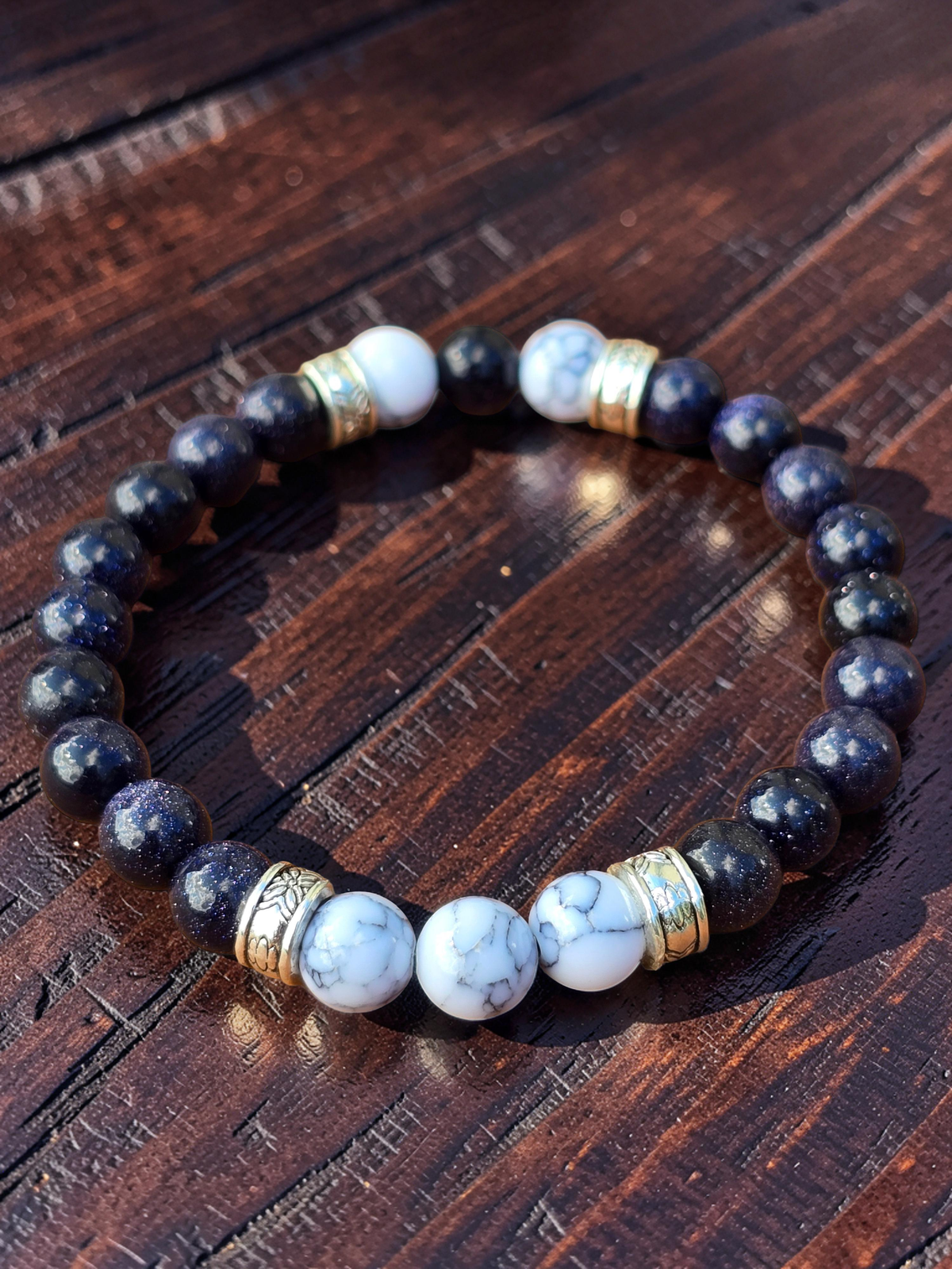 Elasticated Beaded bracelet with midnight blue, white, and silver colours on a wooden surface