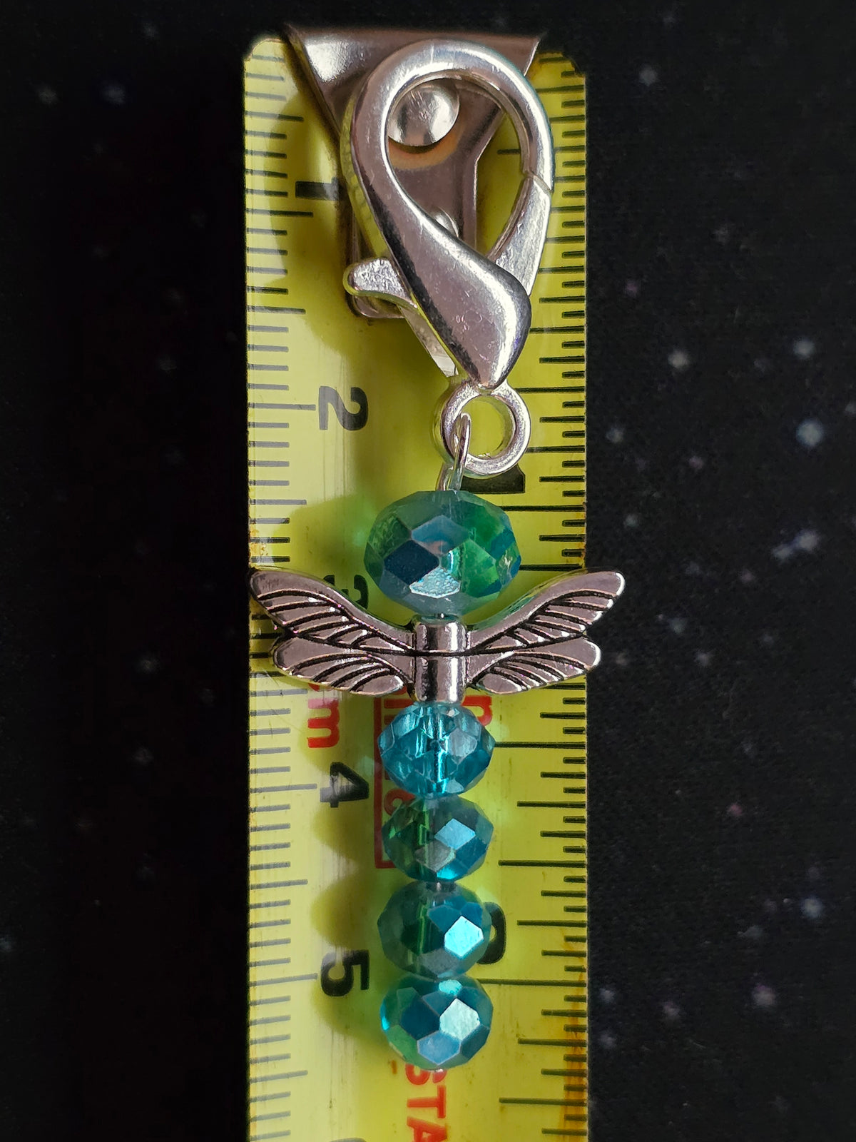 Teal beaded dragonfly zipper charm with silver wings and clasp, shown beside a tape measure for scale.