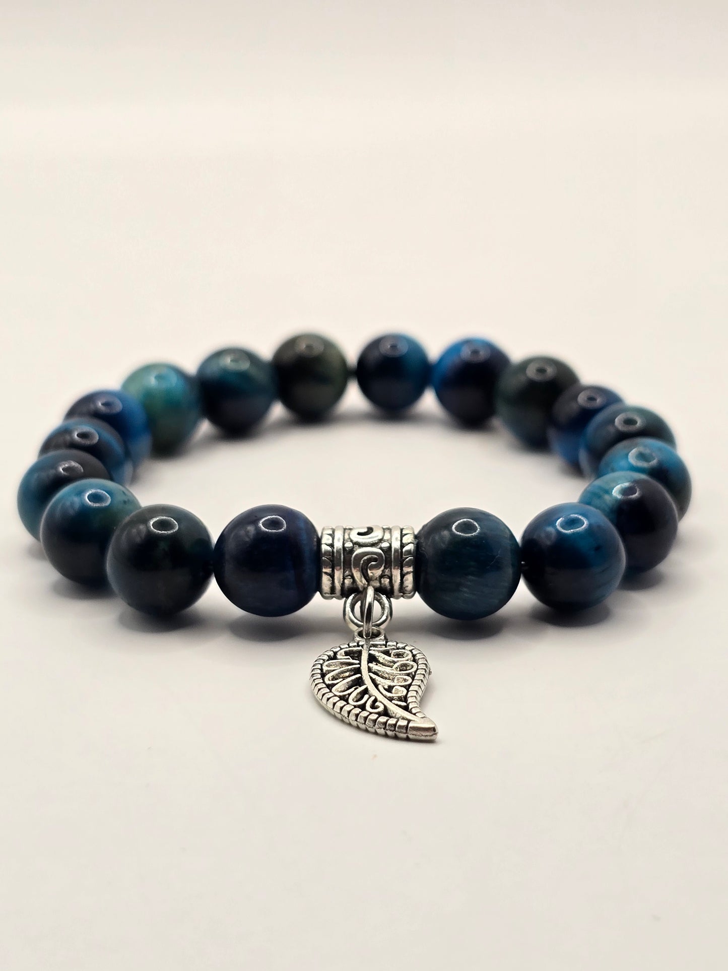 low angle shot of a blue beaded bracelet with metallic silver leaf dangle charm