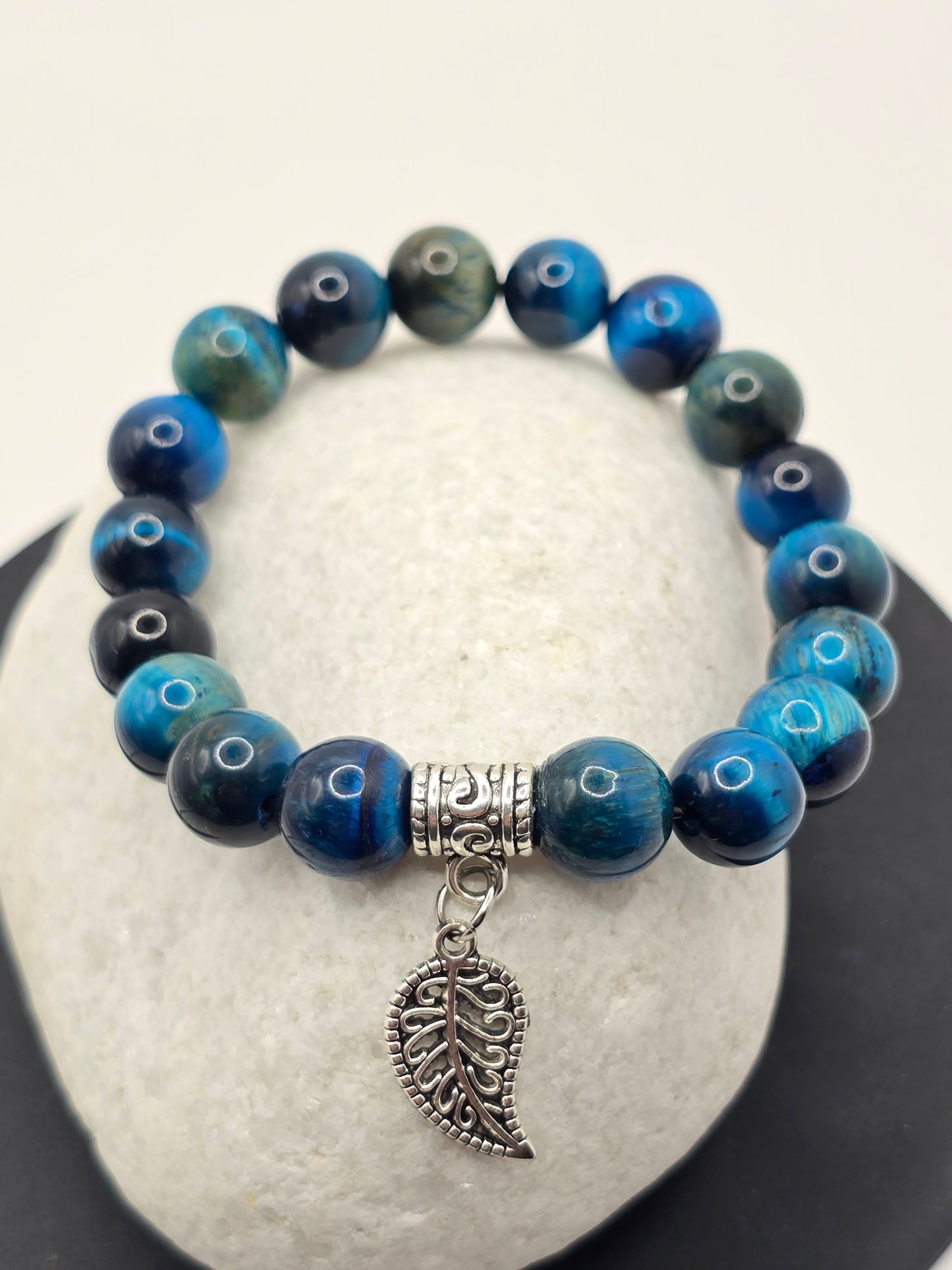 Women's blue bracelet with 1mm beads rests on a white pebble stone