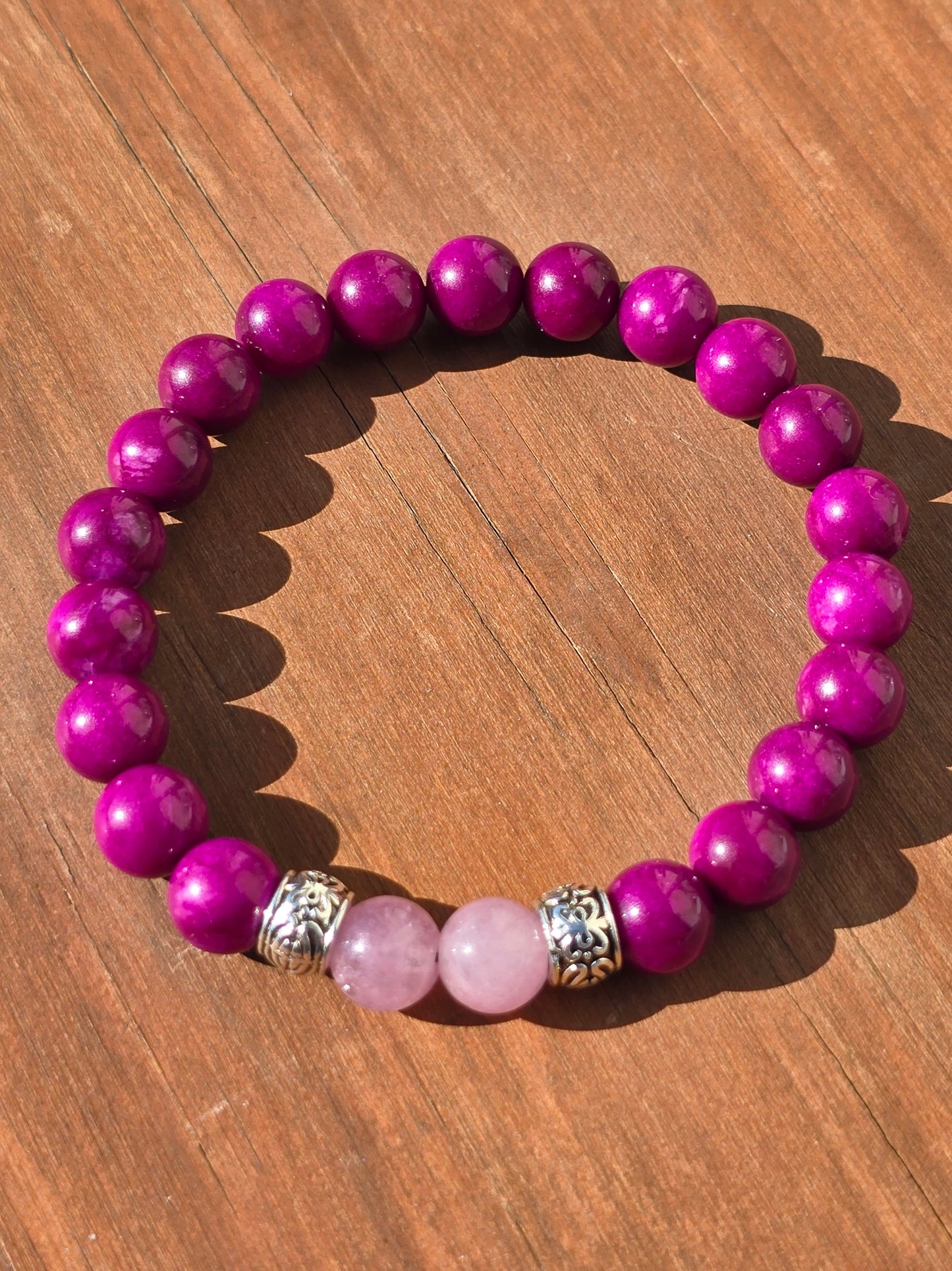 Hot pink and baby pink bracelet with silver spacers on a wooden surface