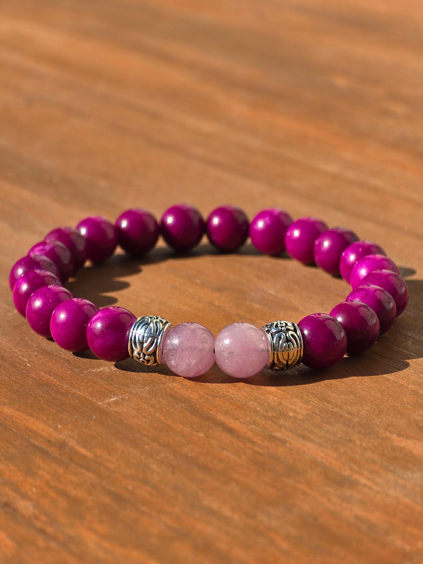 low shot of a ladies stretch beaded bracelet with pink and purple beads on a wooden surface