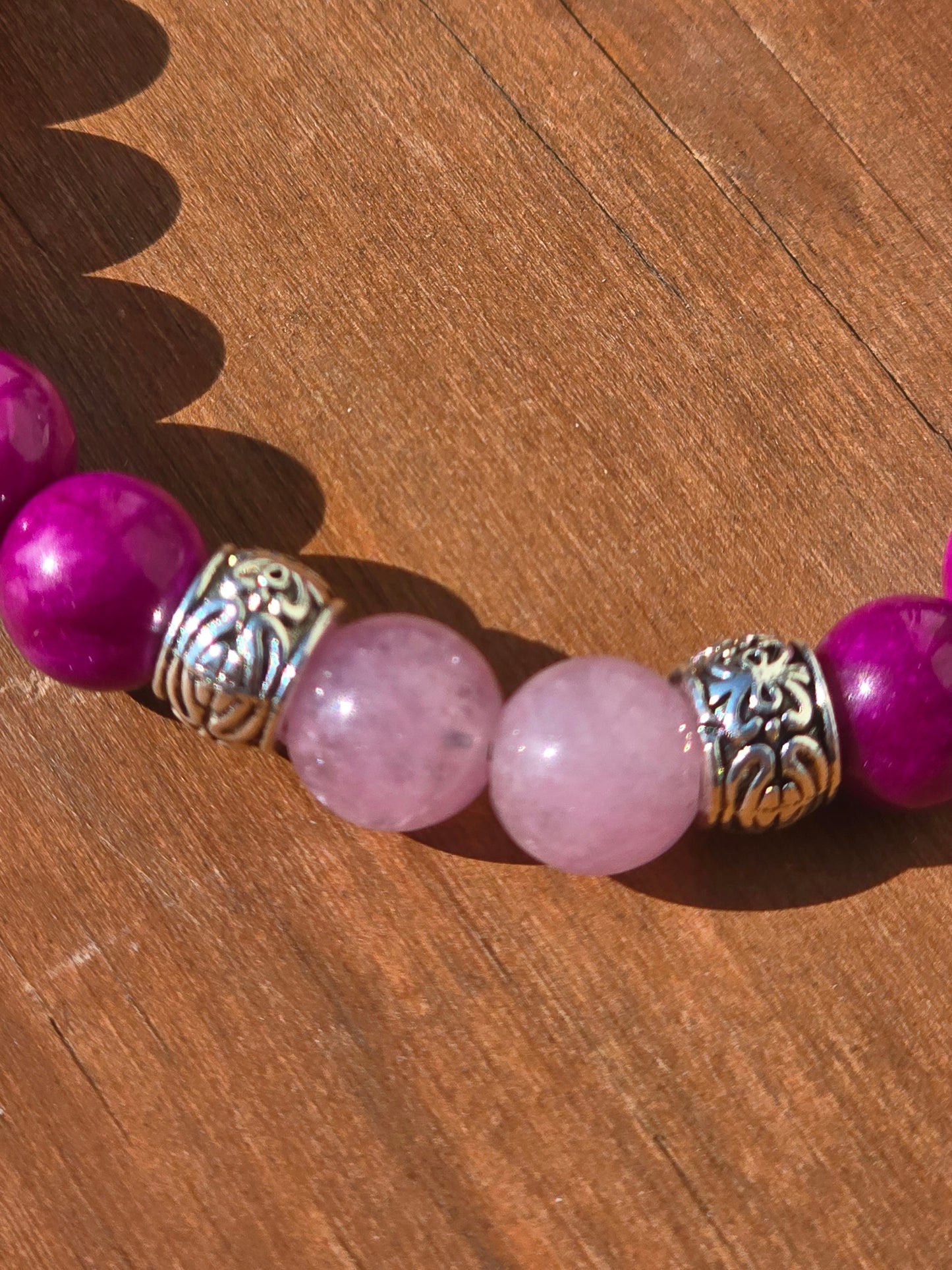 Close-up of a bracelet with pink beads and silver spacers on a wooden surface