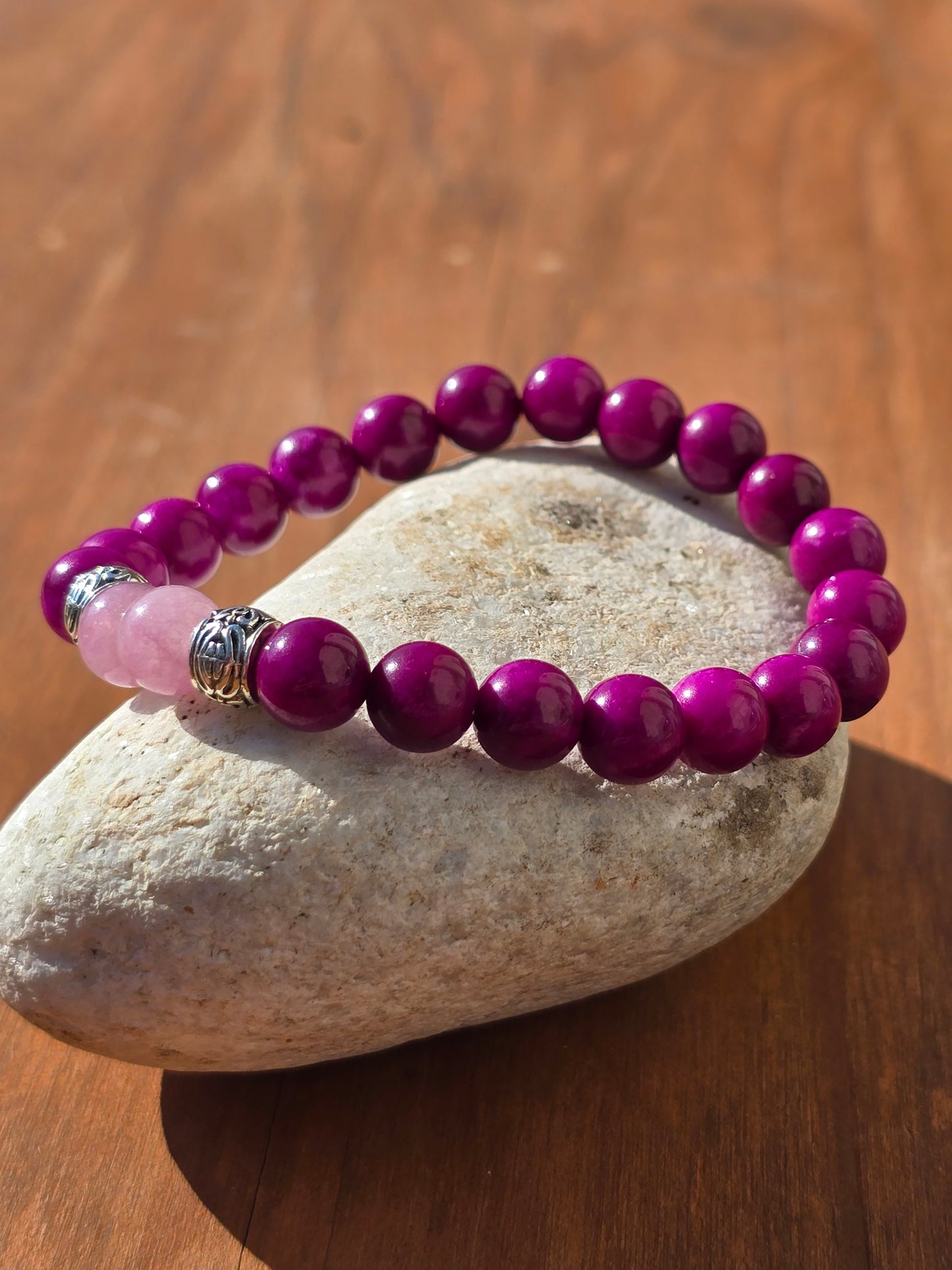 Purple beaded bracelet with pink front beads with silver spacers on a stone pebble