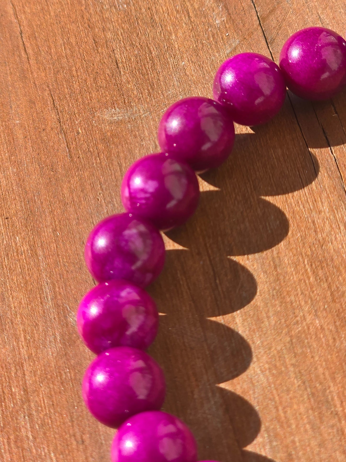 Close-up of a hot pink beaded bracelet on a wooden surface