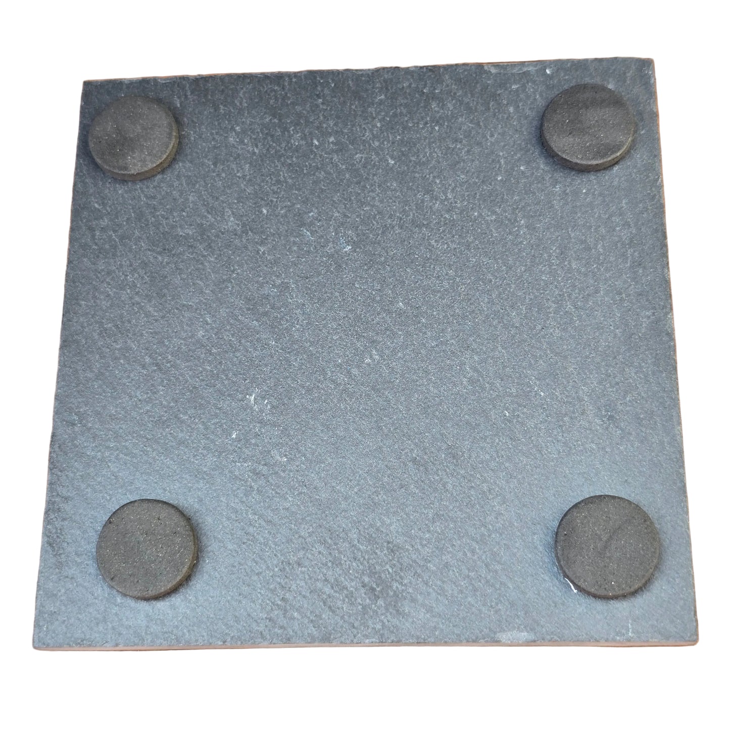 Square piece of gray slate with four circular felt feet on a wooden surface