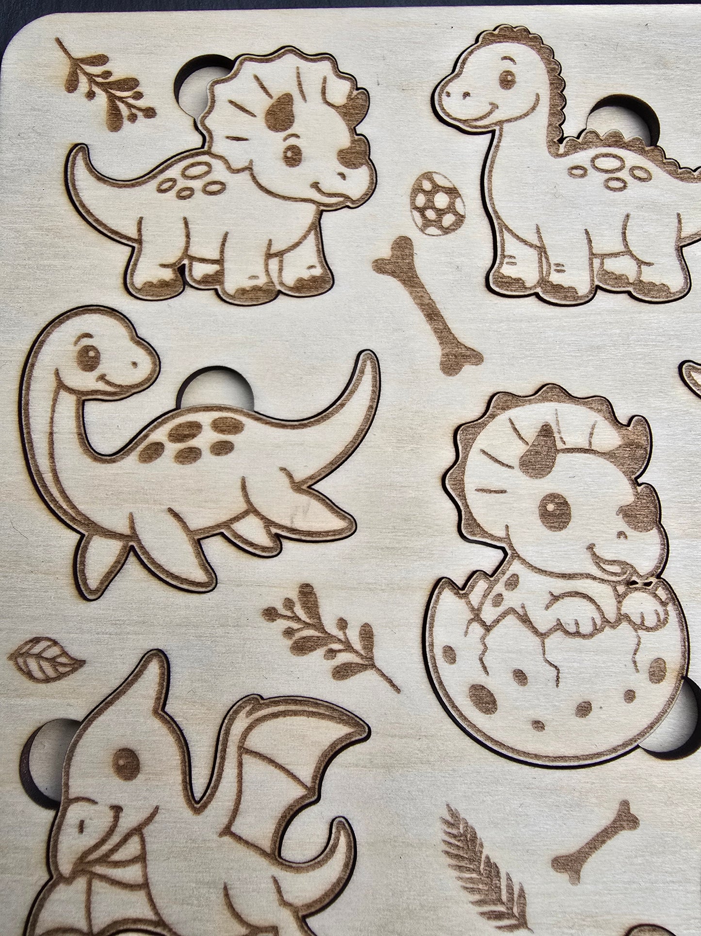 Wooden cutout shapes of dinosaurs and nature elements on a wooden background