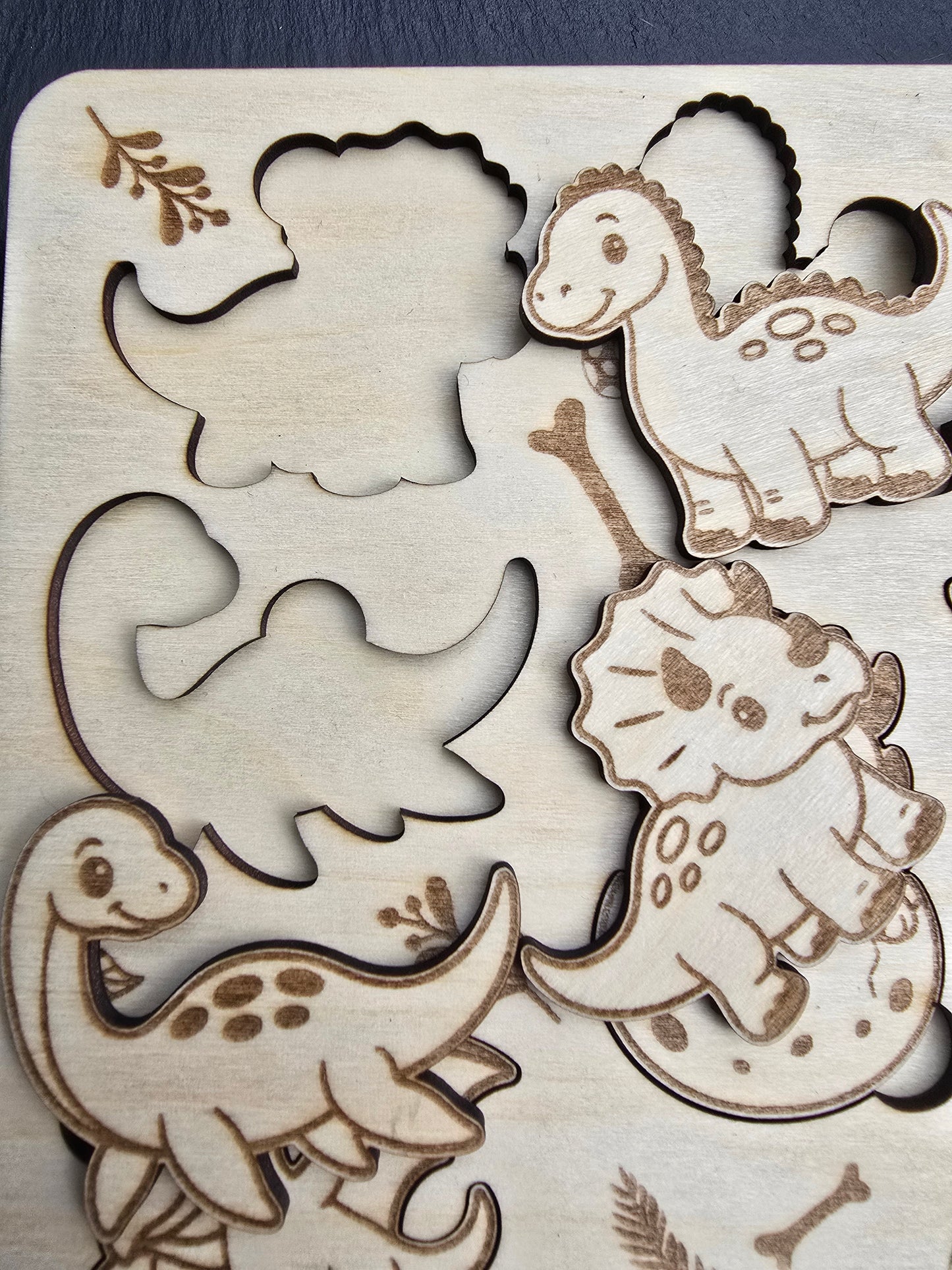 Wooden cut out shapes of Dinosaurs on a wooden board. puzzle for kids