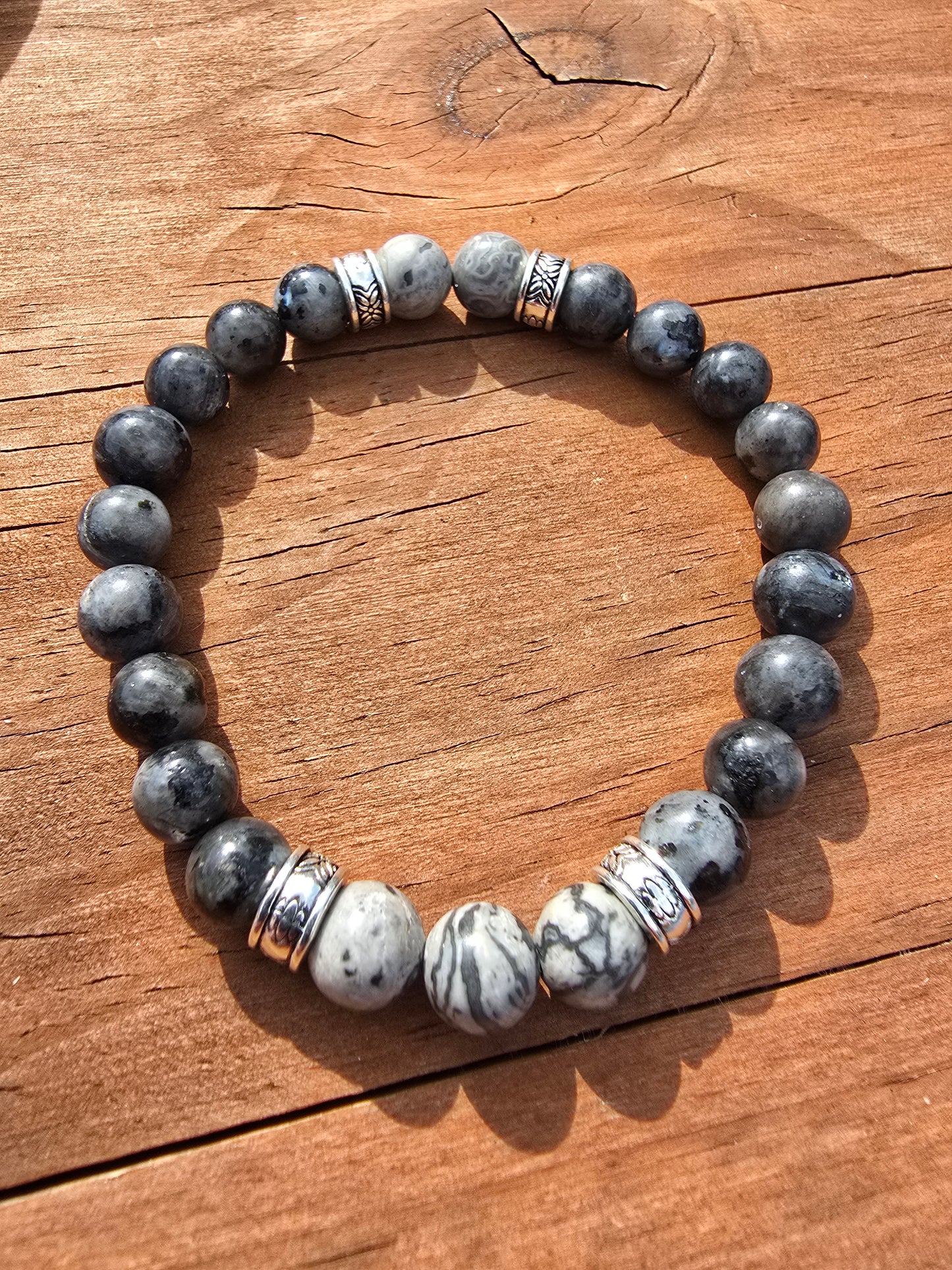 Beaded bracelet with gray and white stones on a wooden surface