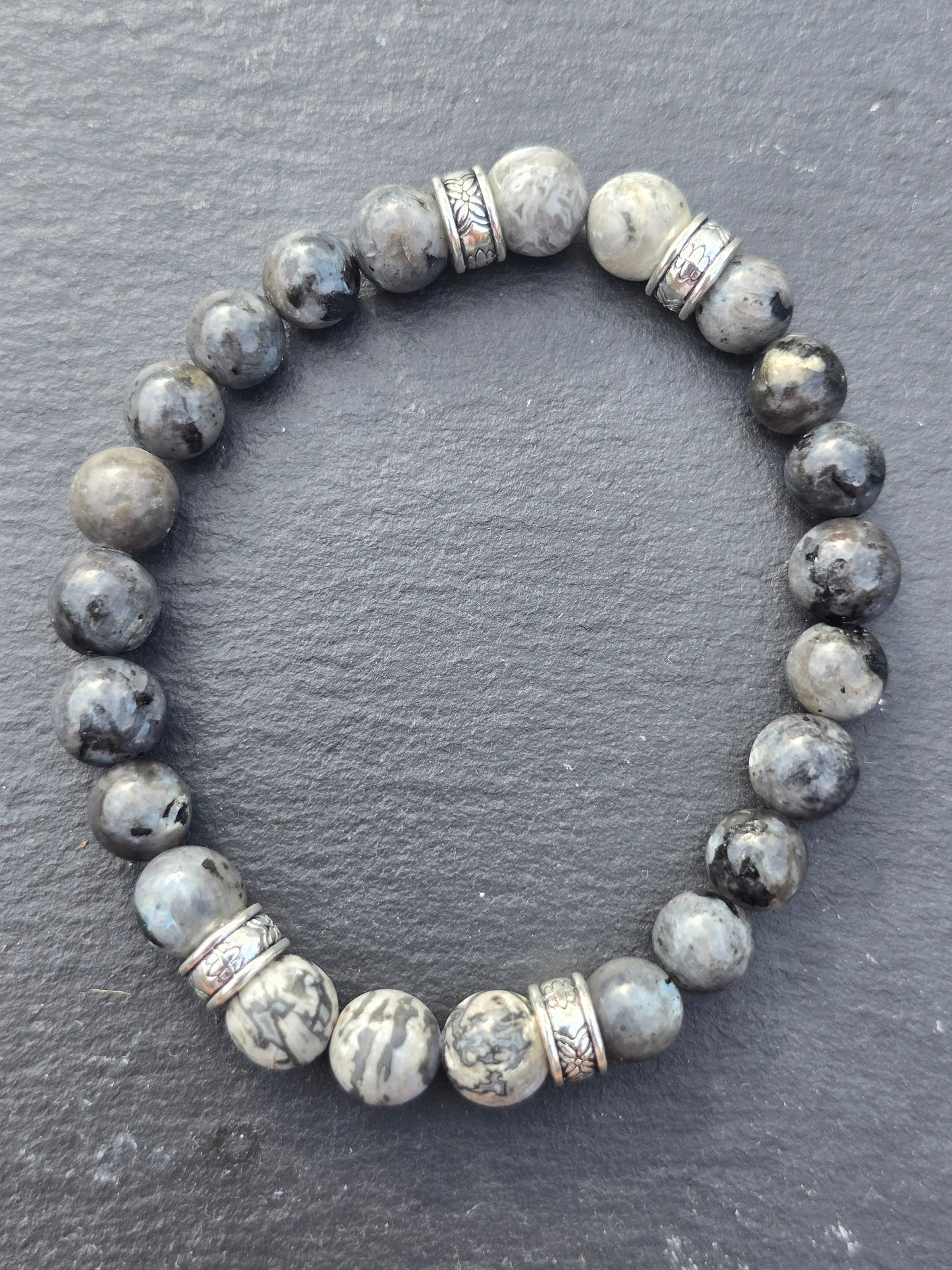 Grey beaded bracelet with silver accents on a dark grey slate background