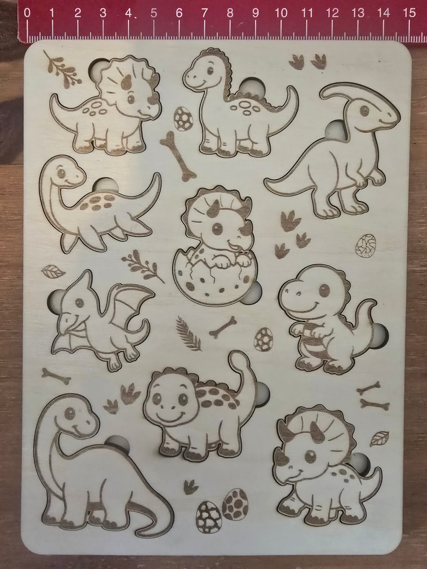 Dinosaur-themed wooden puzzle with measurement scale showing 15cm wide