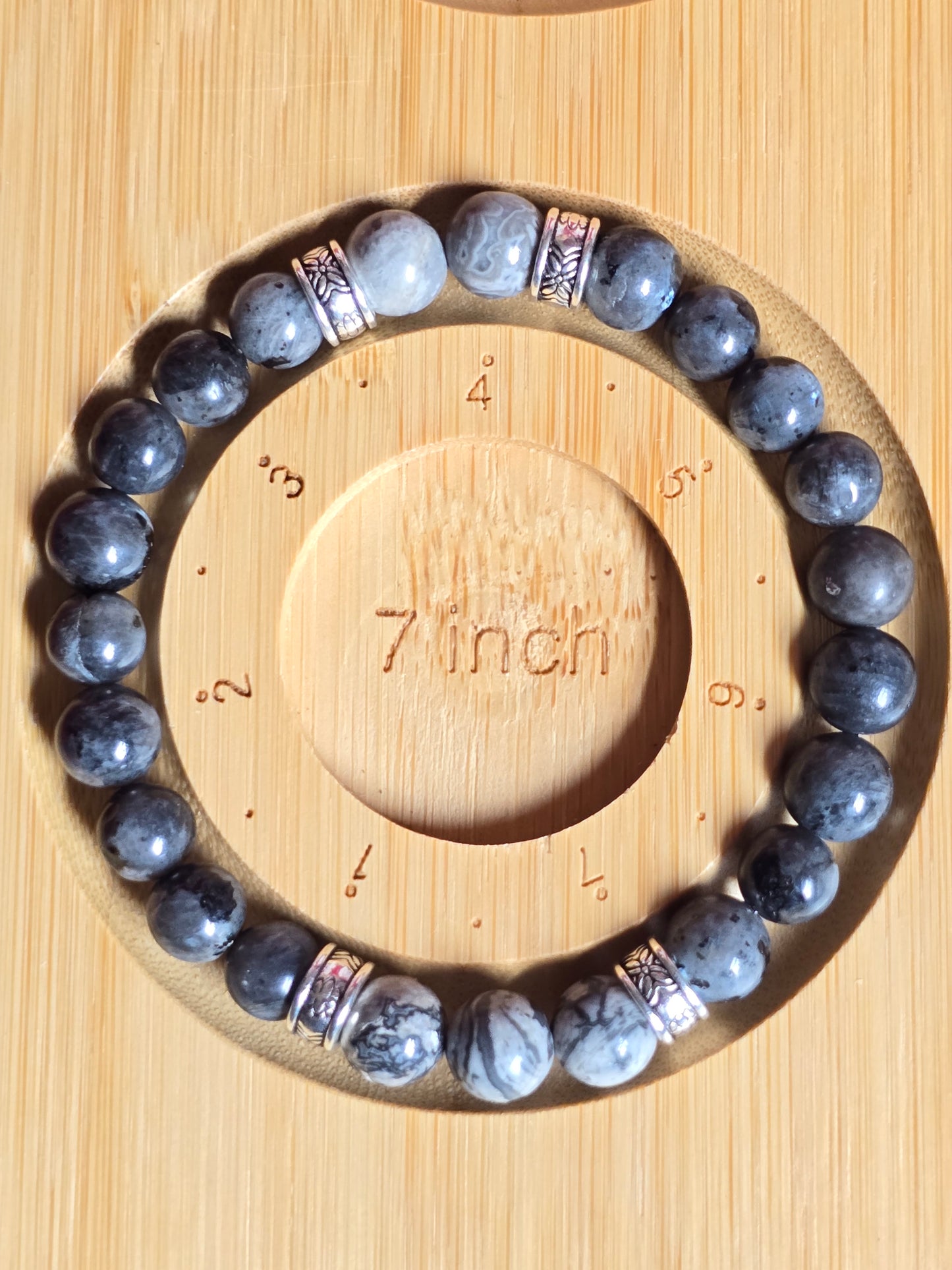 Grey charcoal beaded bracelet on a wooden measuring tool showing 7 inch size