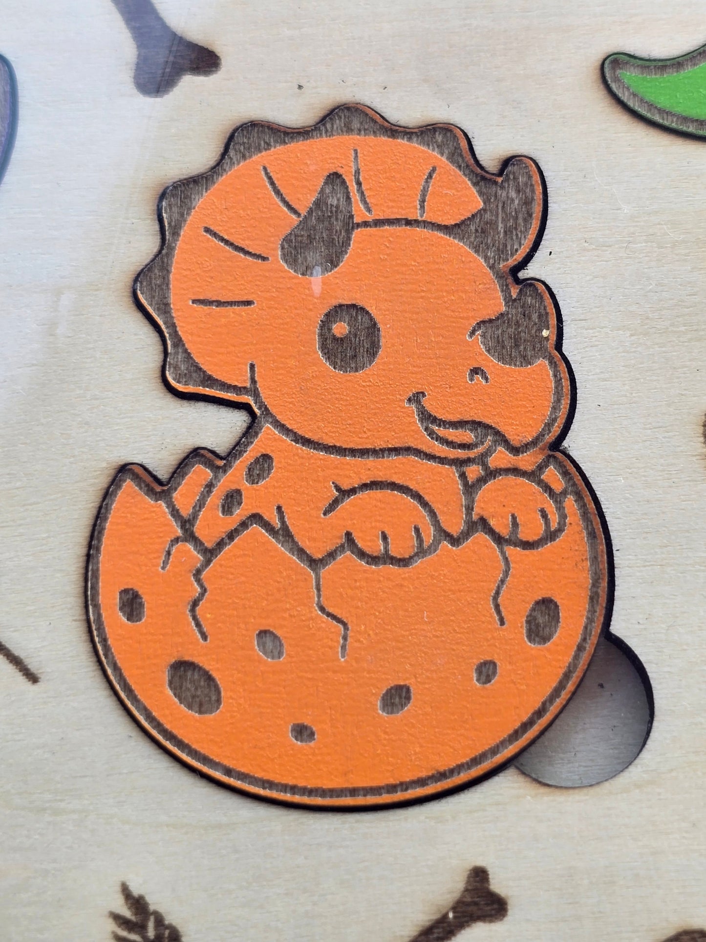 Orange coloured wooden baby dinosaur in an egg puzzle piece as part of a children's wooden puzzle game