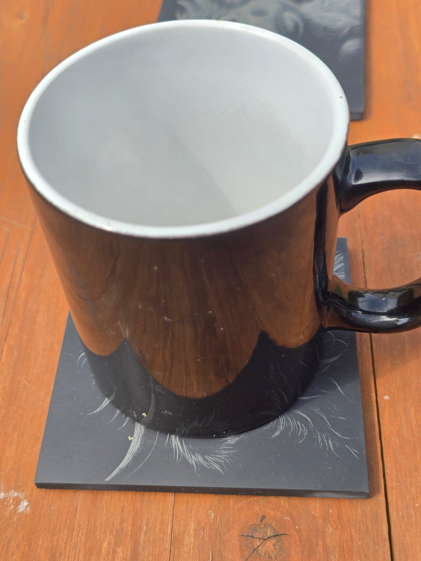 Black mug with white interior on a highland cow slate coaster