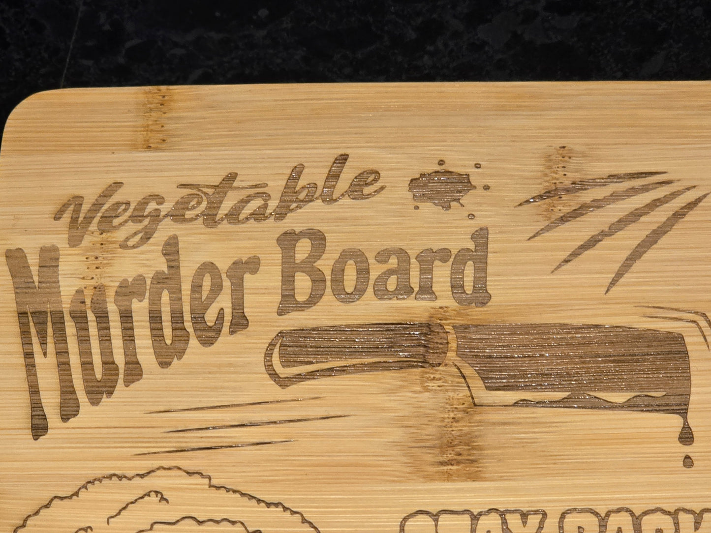 Wooden cutting board with 'Vegetable Murder Board' engraving and a knife illustration.