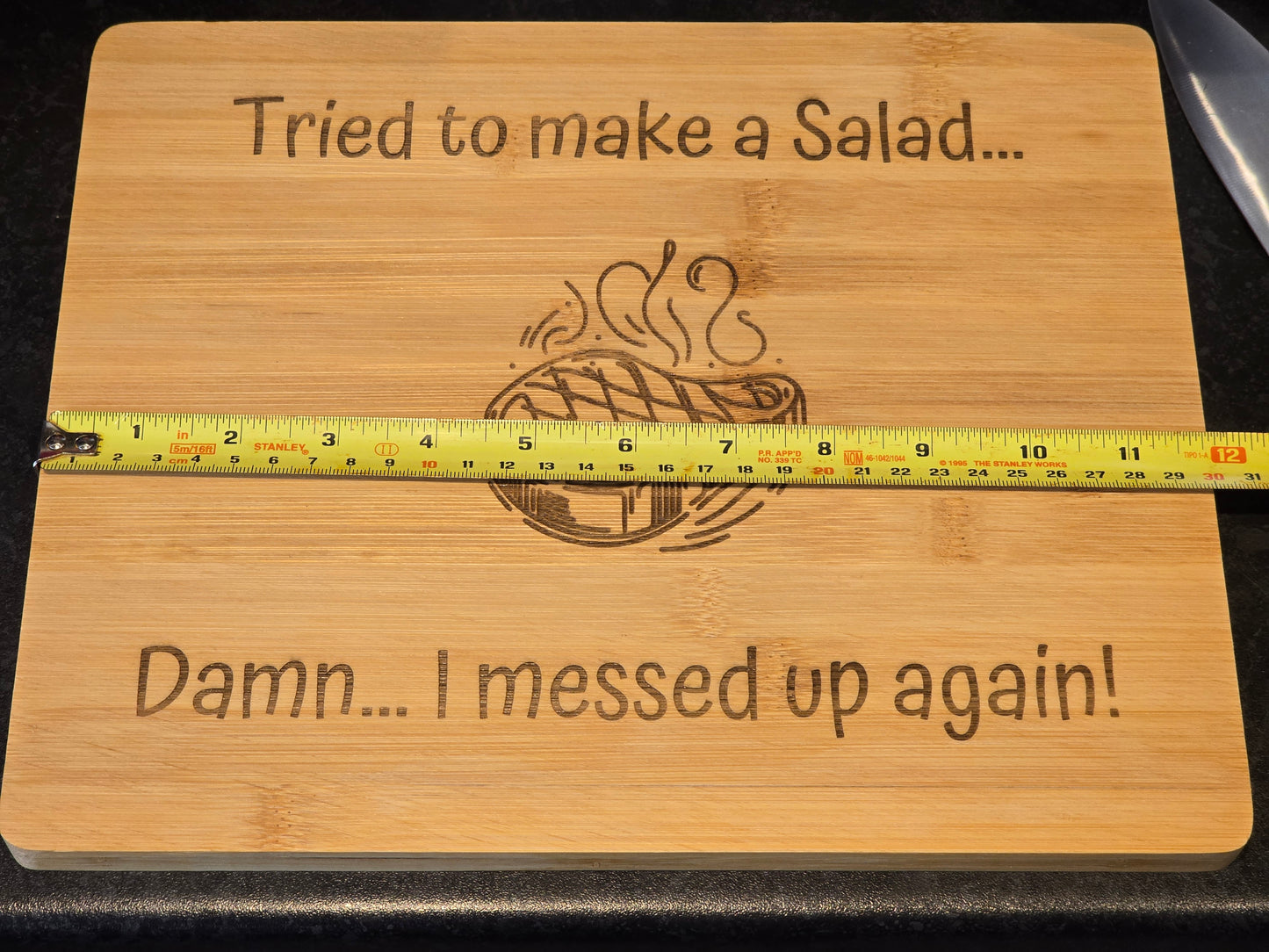 Wooden cutting board with humorous text and a measuring tape showing 30cm length