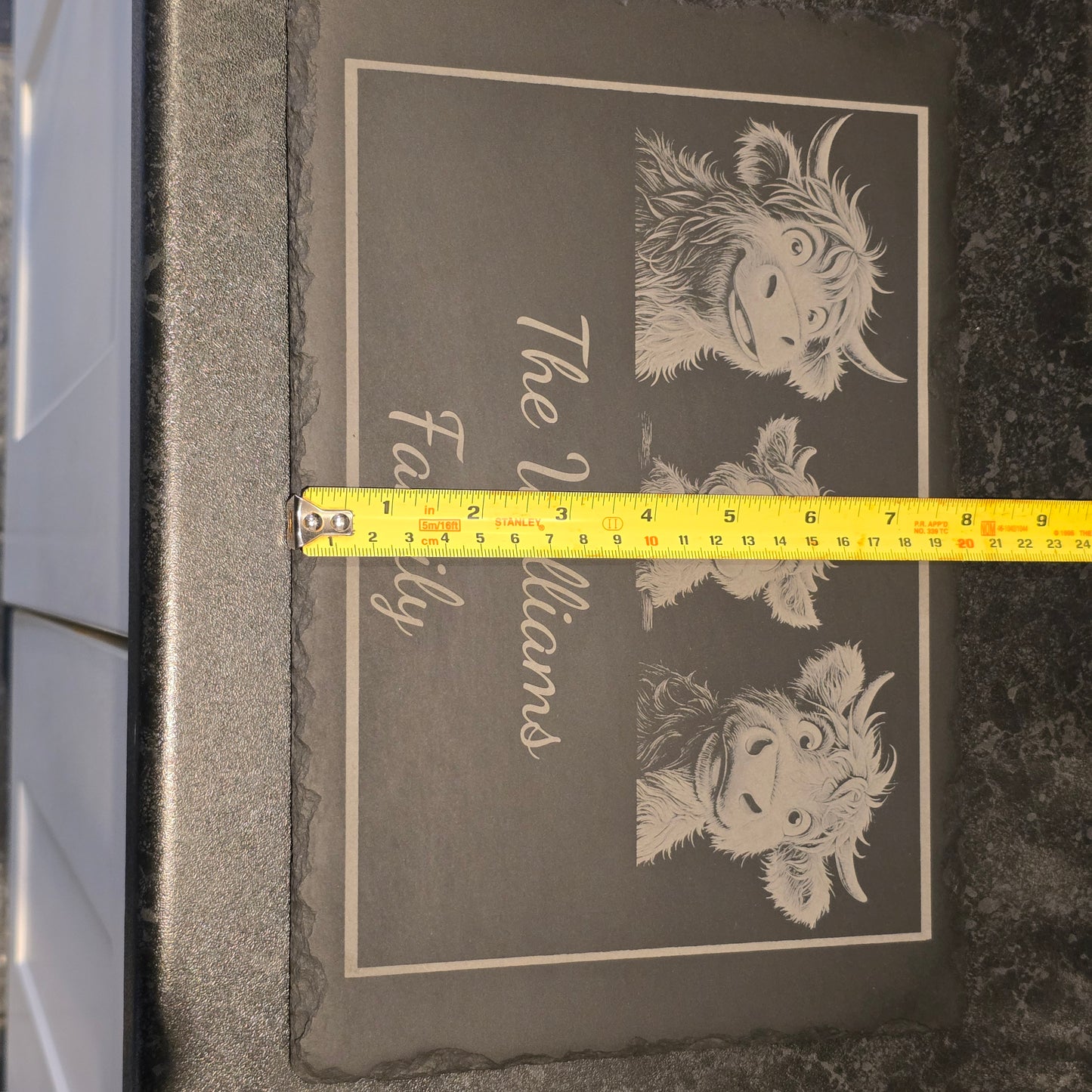 Slate with cow illustration and 'The Williams Family' text, measured by a tape measure showing 21cm width