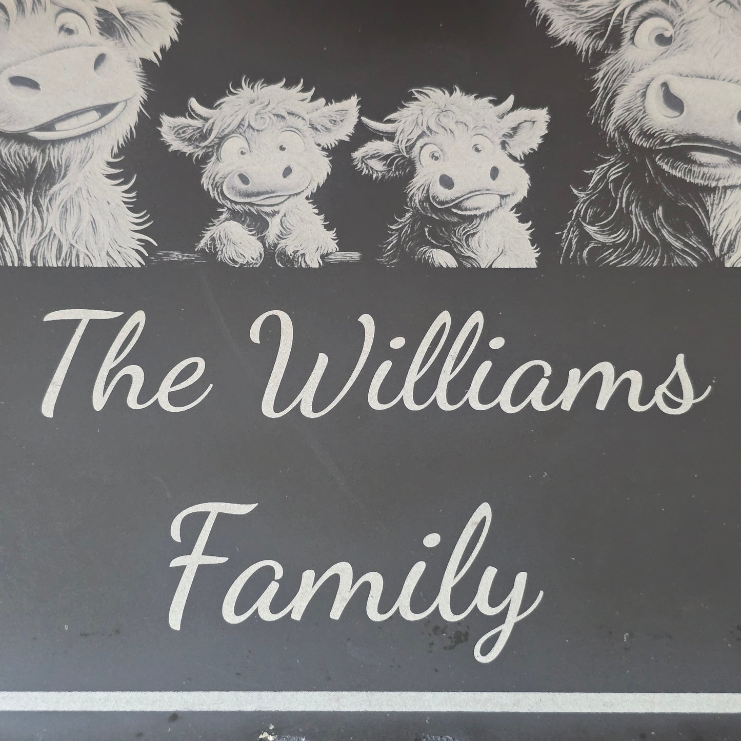 Engravings of highland cows with 'The Williams Family' text on a dark slate background