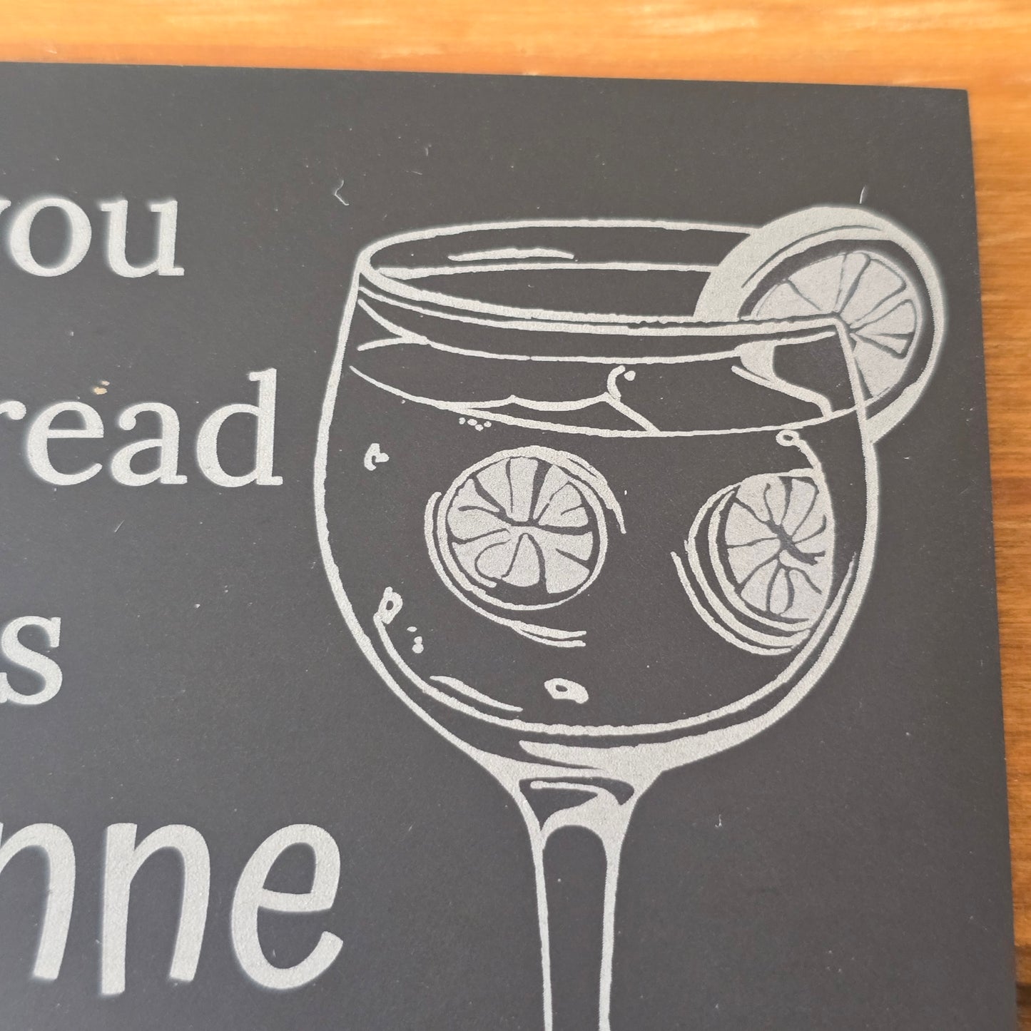 Slate coaster with a glass of gin and lemon slices on a dark background