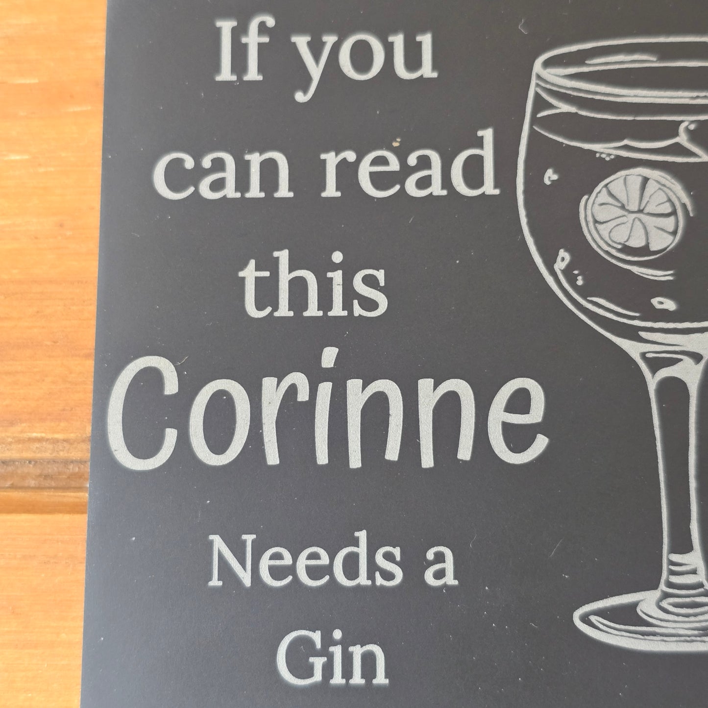 Engraved wooden sign with text 'If you can read this Corinne Needs a Gin' on a dark background.
