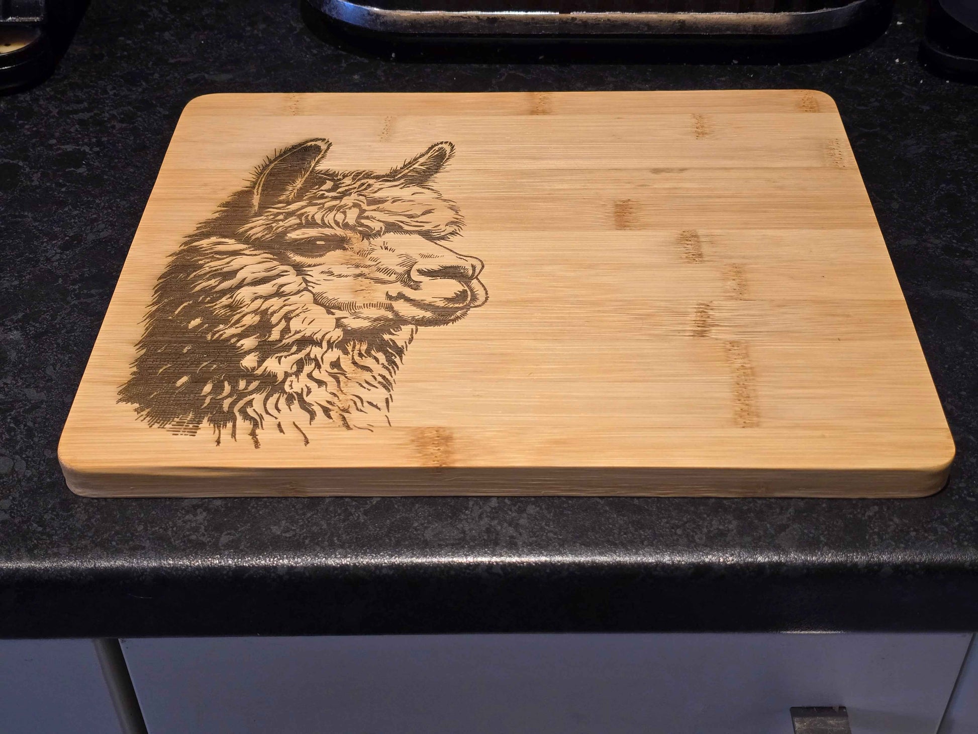 Bamboo Chopping board with engraved alpaca design on a dark surface
