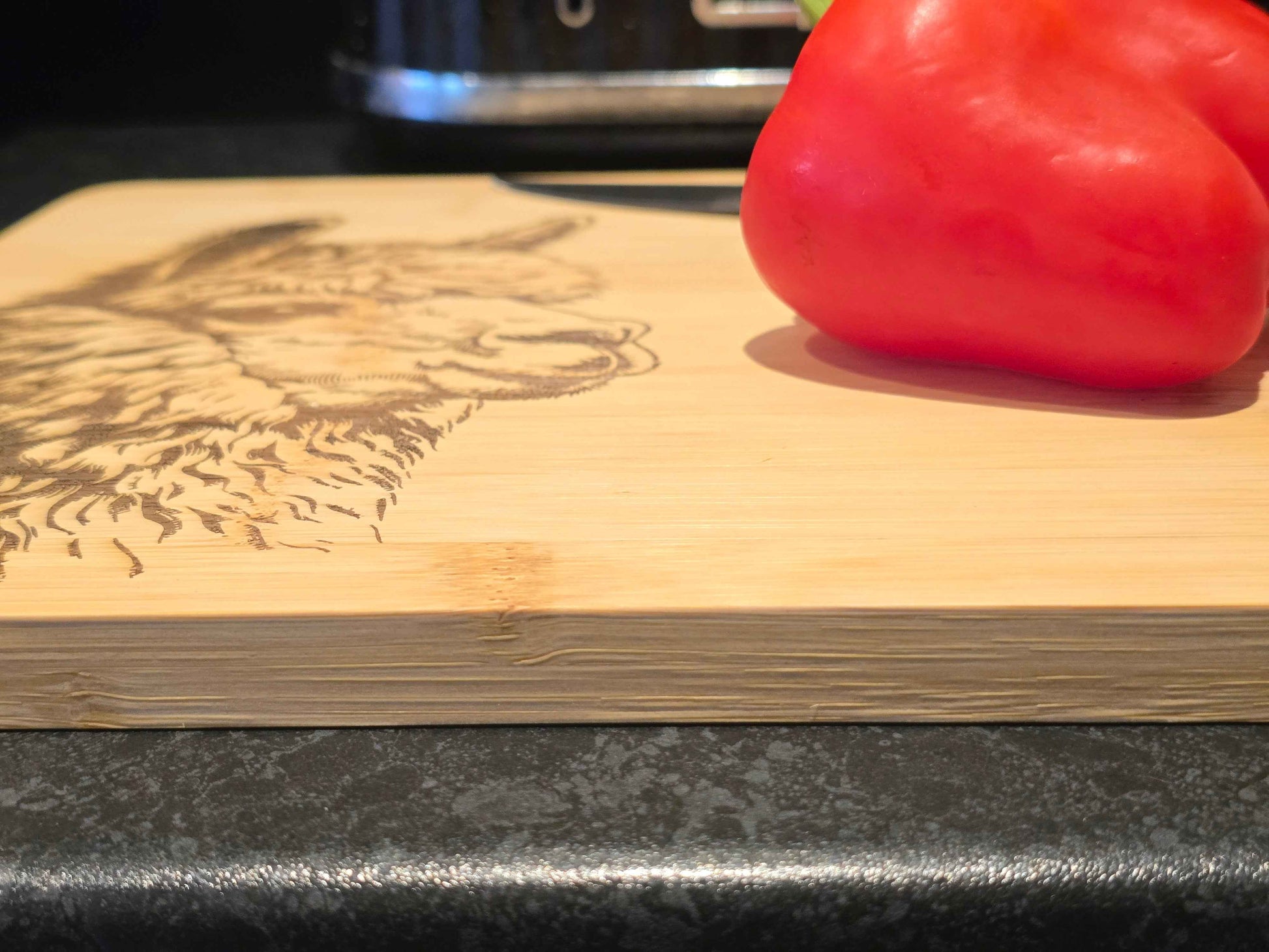 Red bell pepper on a wooden cutting board with a engraved alpaca design
