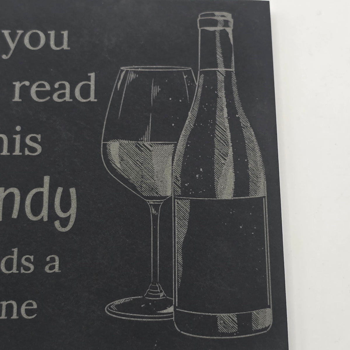 slate coaster with an engraving of a wine bottle and glass