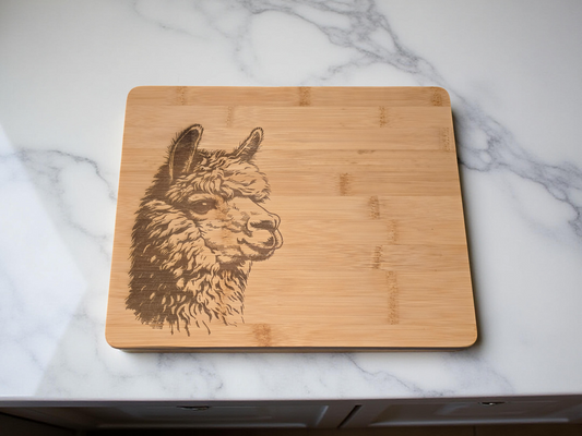 Bamboo cutting board with engraved alpaca design on a marble surface