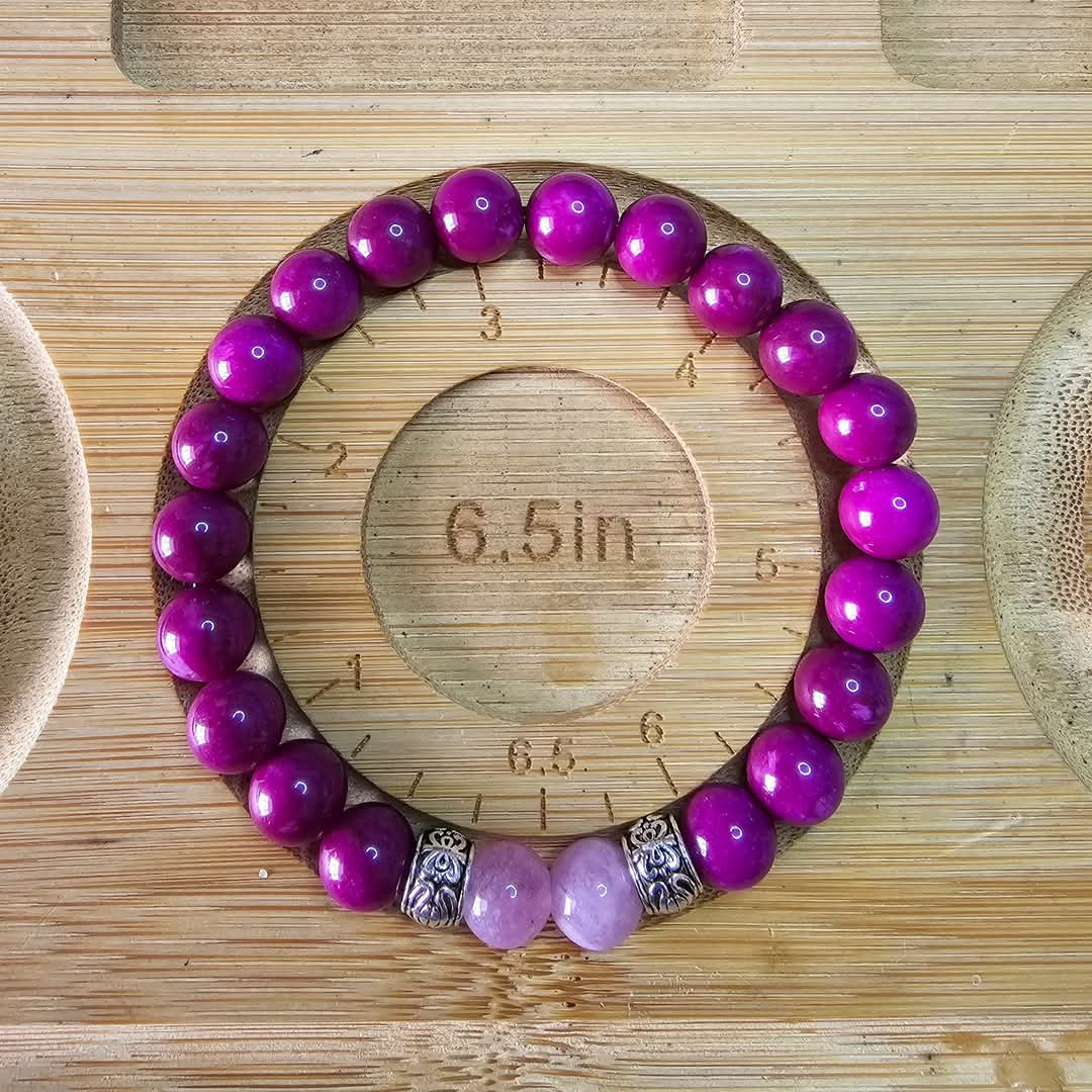 Women's Beaded bracelet with purple and pink beads on a wooden surface with measurement markings showing the size as 6.5inches.