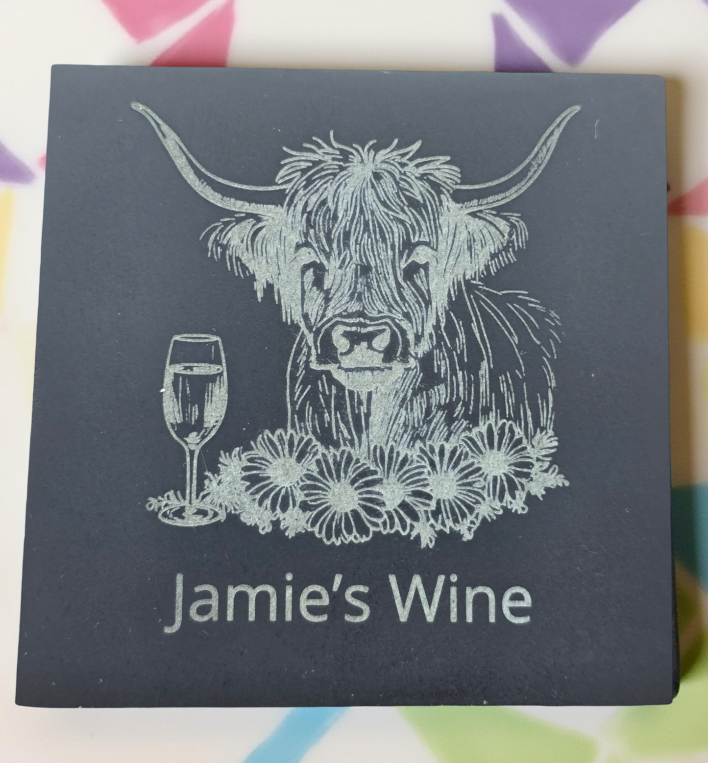 Dark gray box with a highland cow illustration and 'Jamie's Wine' text on a multicolored geometric pattern background.
