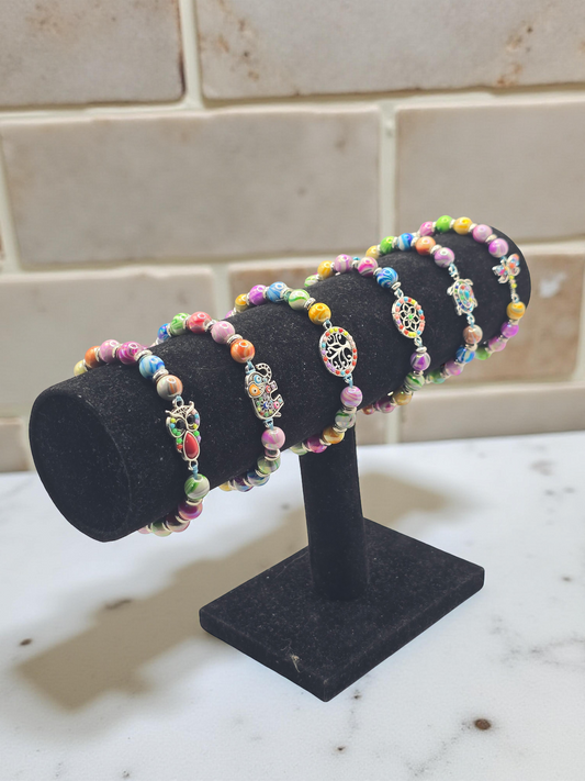 Colorful beaded bracelets on a black stand against a tiled wall background