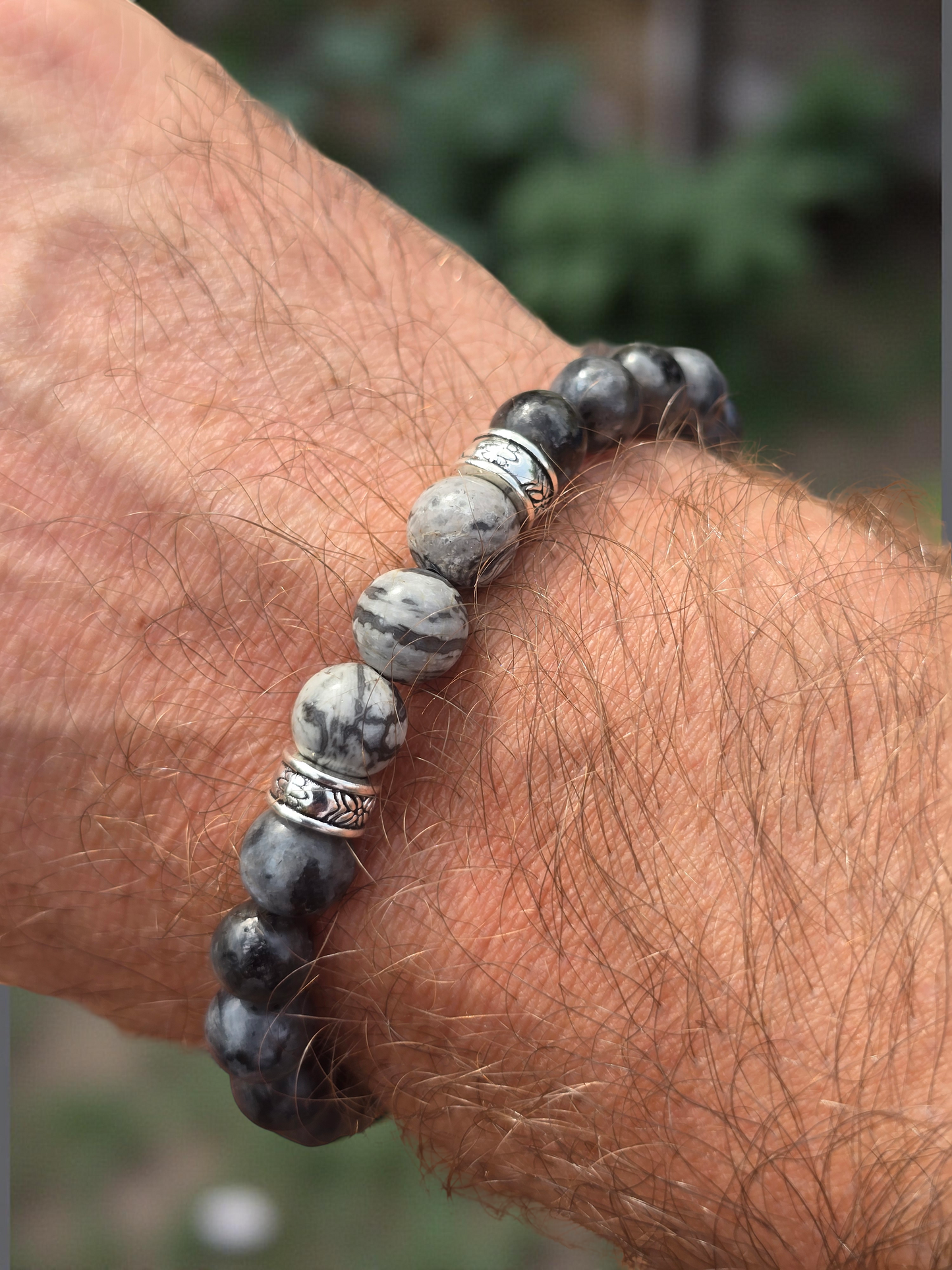 Close-up of a wrist wearing a beaded bracelet with a natural stone pattern.
