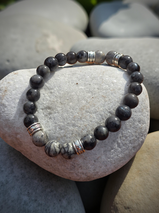 Men's charcoal grey beaded bracelet on a white stone pebble