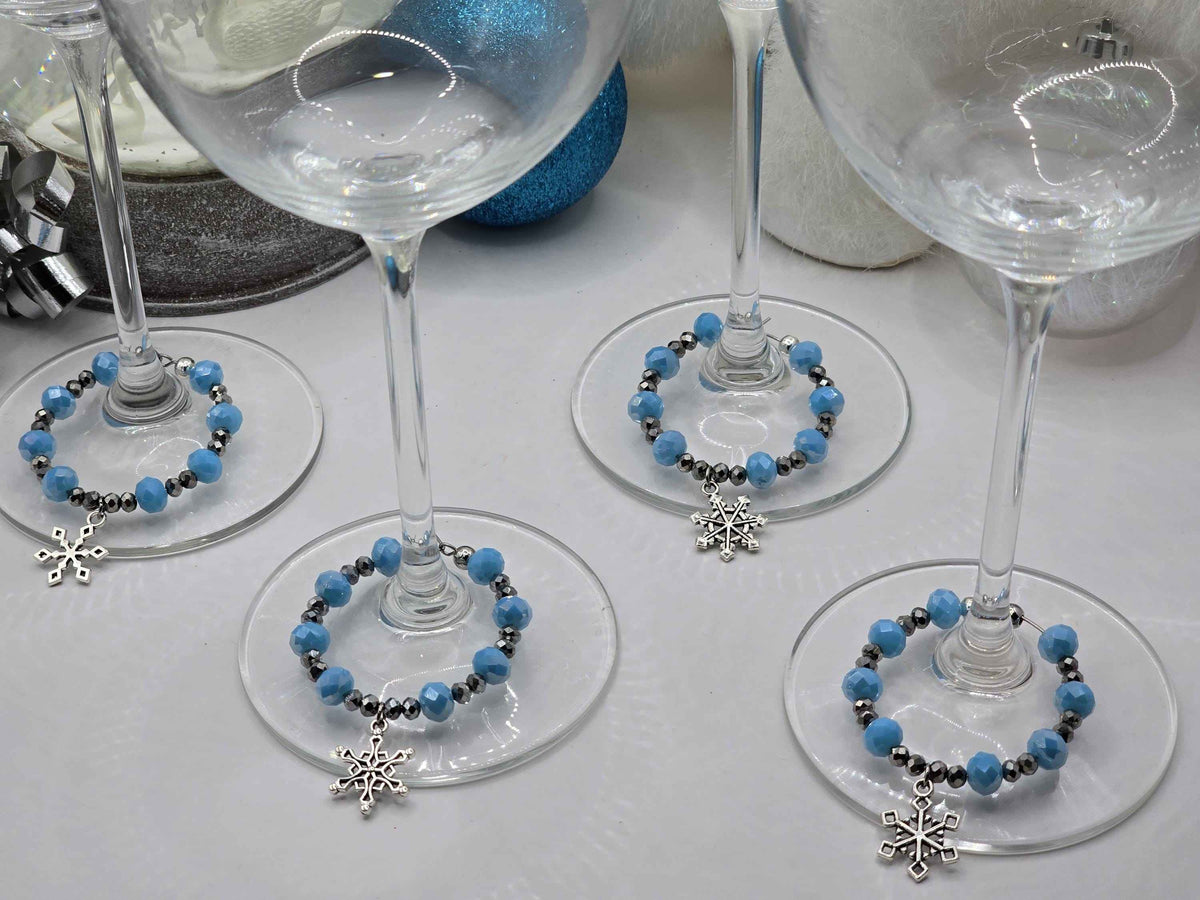 Wine glass stems decorated with blue and silver beaded charms featuring dangling snowflake pendants.