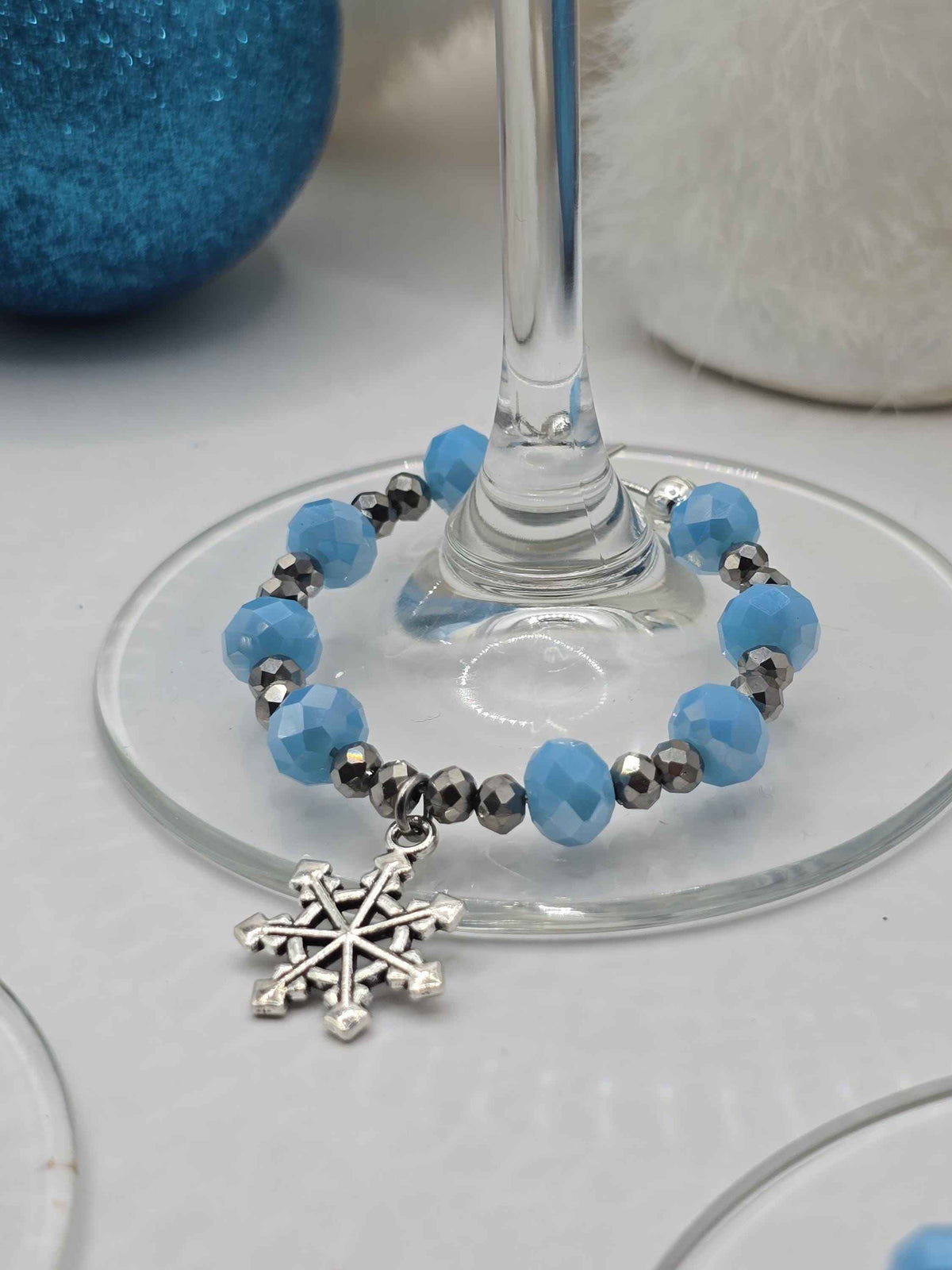 Wine glass charm with light blue and silver faceted beads and a dangling snowflake pendant.