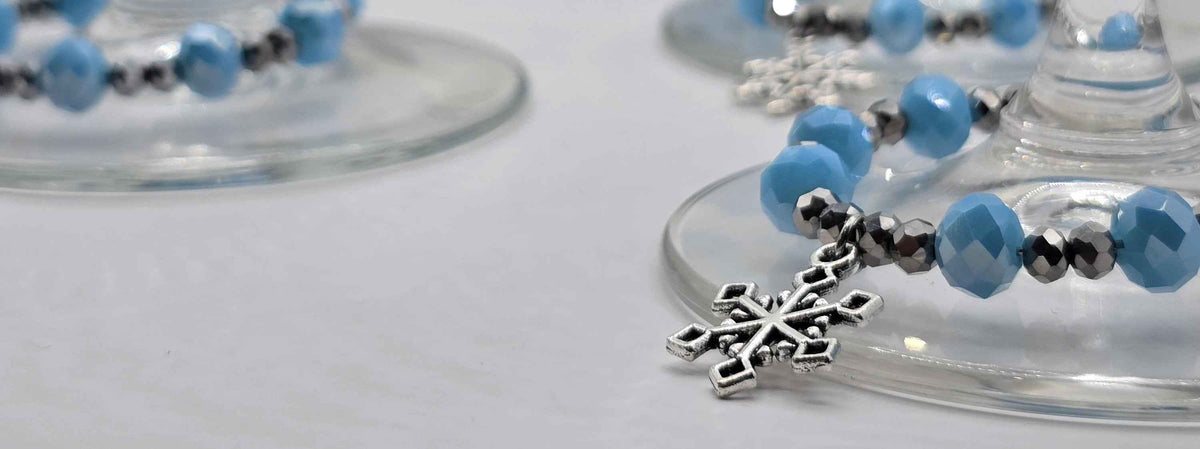Silver snowflake charm with faceted blue and silver beads wrapped around the stem of a wine glass.