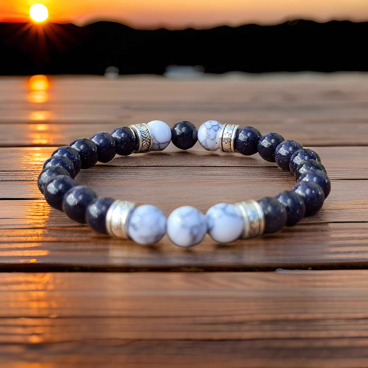 Mens Beaded bracelet with blue and white stones on a wooden surface with sunset reflection