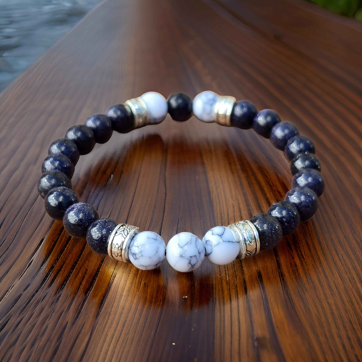 Beaded bracelet with black and white stone beads and silver accents on a wooden surface