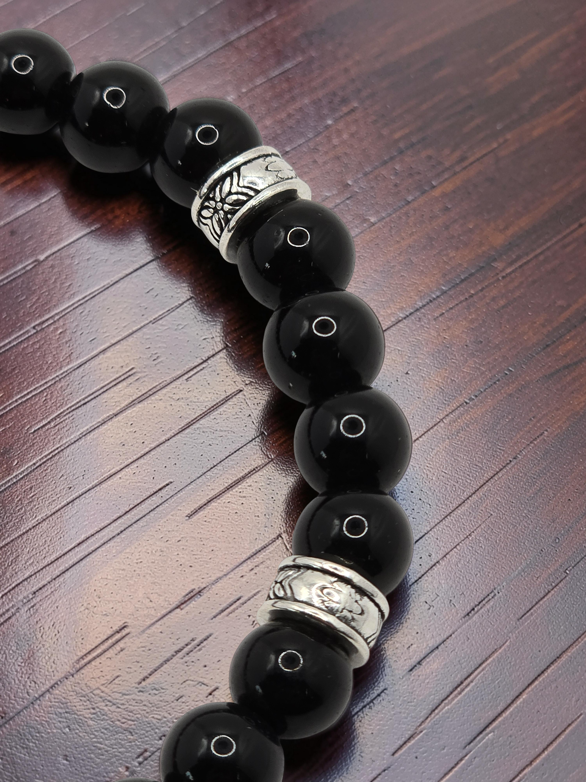 close up of a men's black beaded bracelet with metal alloy silver spacers