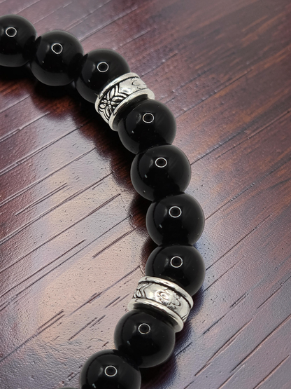 close up of a men's black beaded bracelet with metal alloy silver spacers