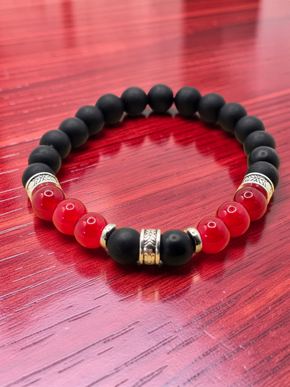 mens Black, red, and gold silver bracelet on a red wooden surface