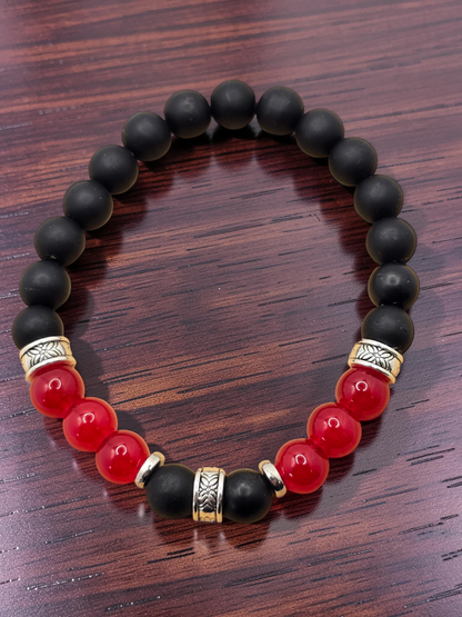 Black and red beaded bracelet with gold accents on a wooden surface
