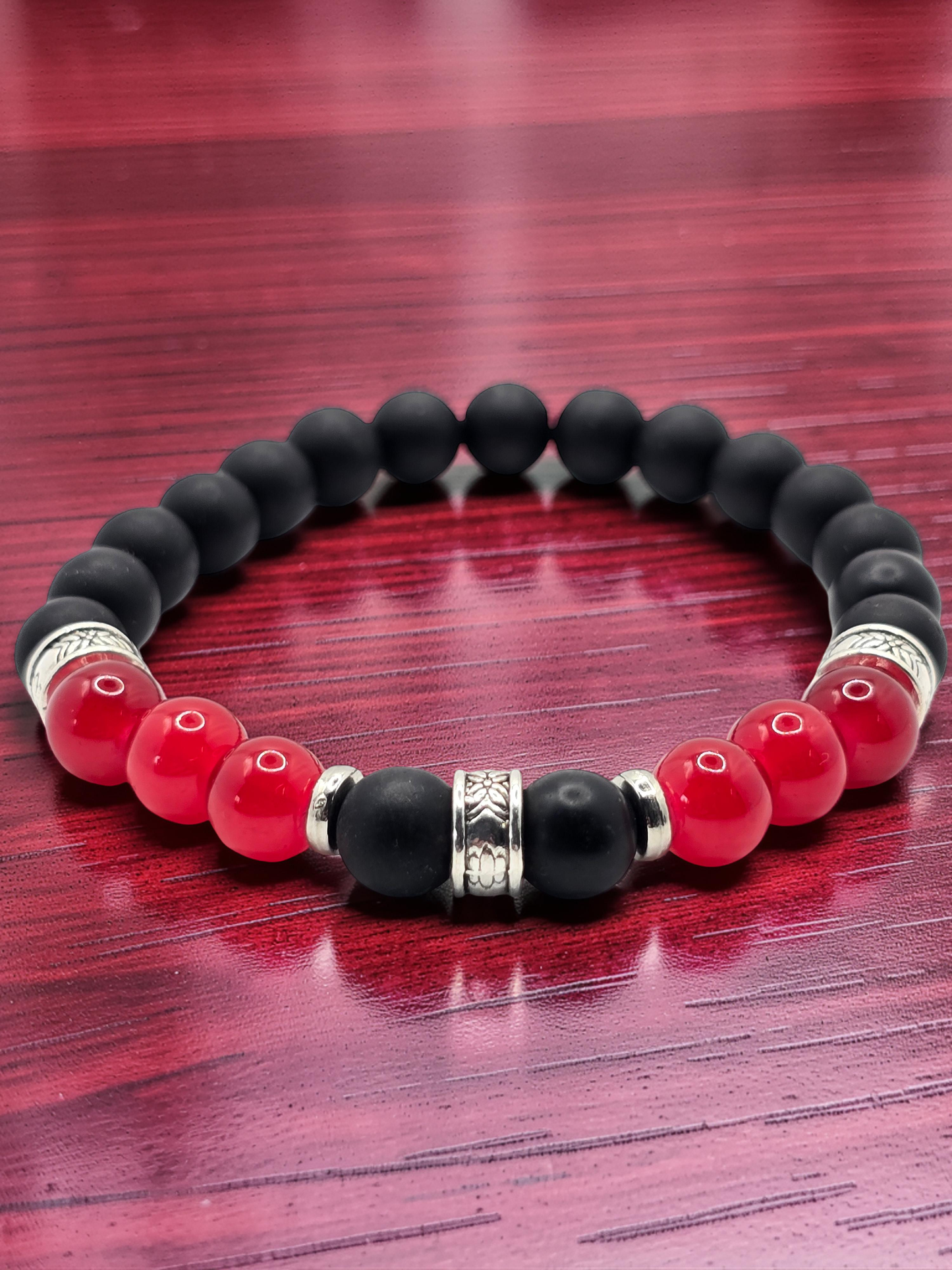 Mens 6 inch Black, red, and silver beaded bracelet on a wooden surface