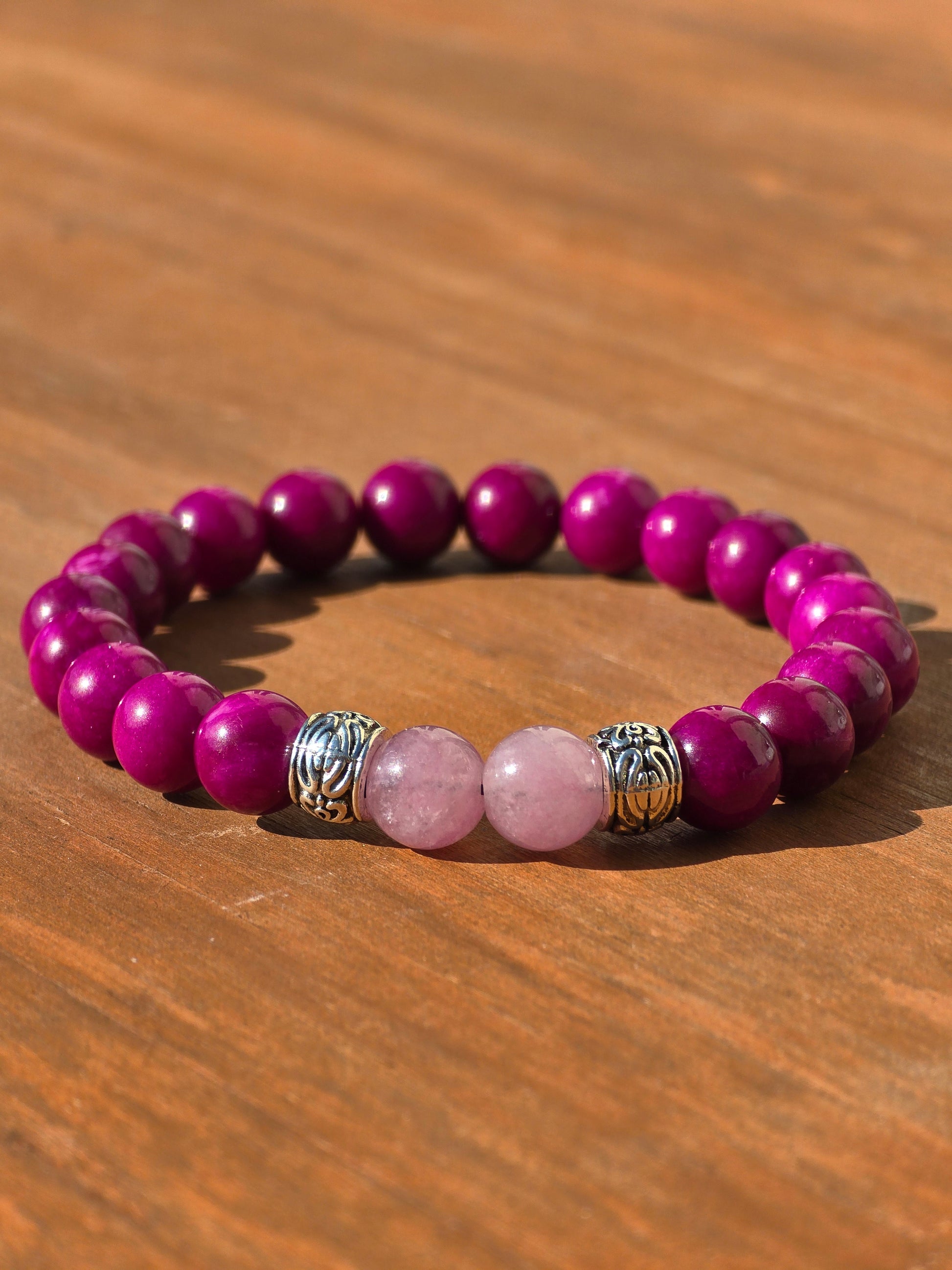low shot of a ladies stretch beaded bracelet with pink and purple beads on a wooden surface