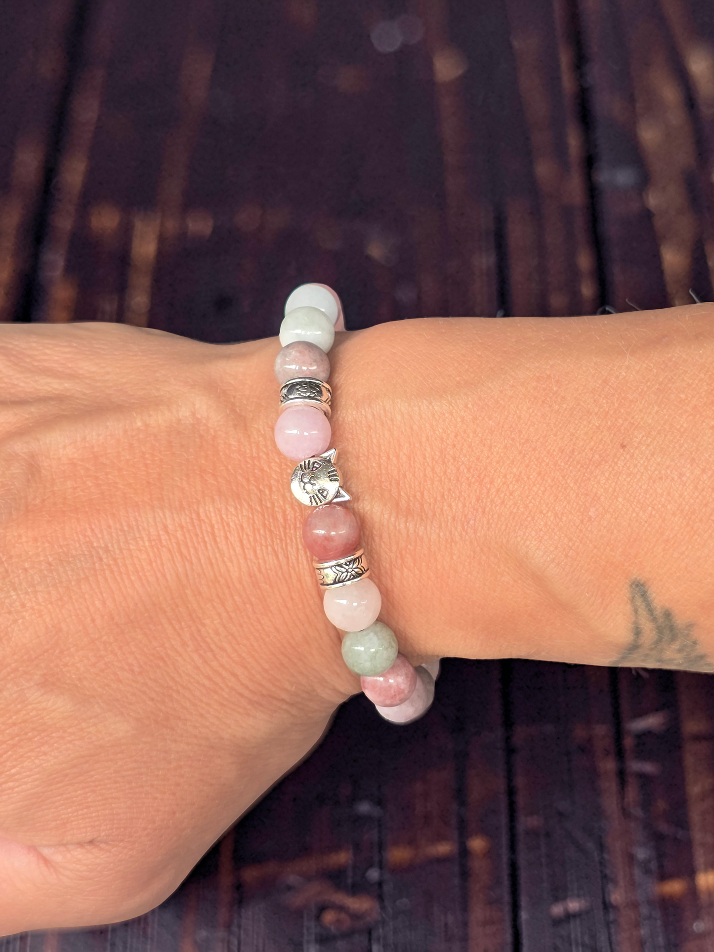 Close-up of a ladies wrist wearing a beaded bracelet with silver cat charms