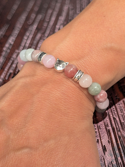 elasticated cat Bracelet with pink and green beads on a wrist against a patterned background