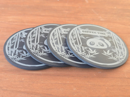 Four black coasters with lying panda and bamboo designs on a wooden surface