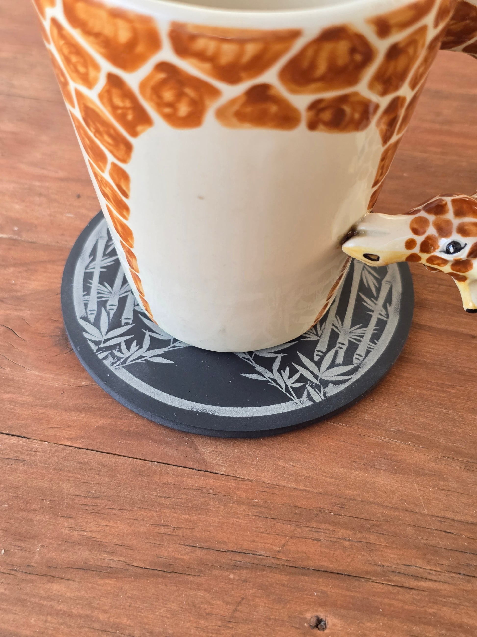 Giraffe-shaped cup on a wooden surface with a coaster underneath