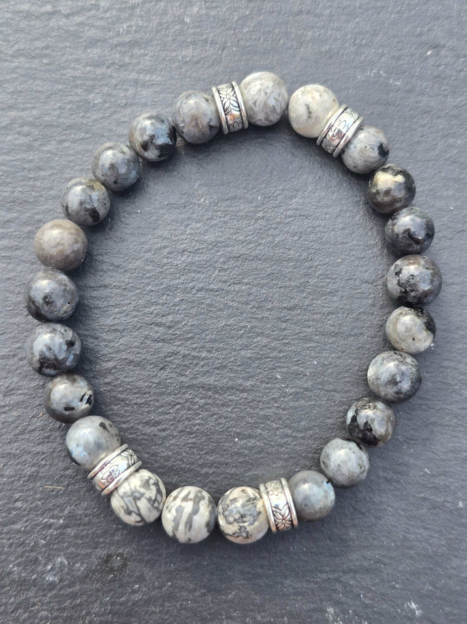 Grey beaded bracelet with silver accents on a dark grey slate background
